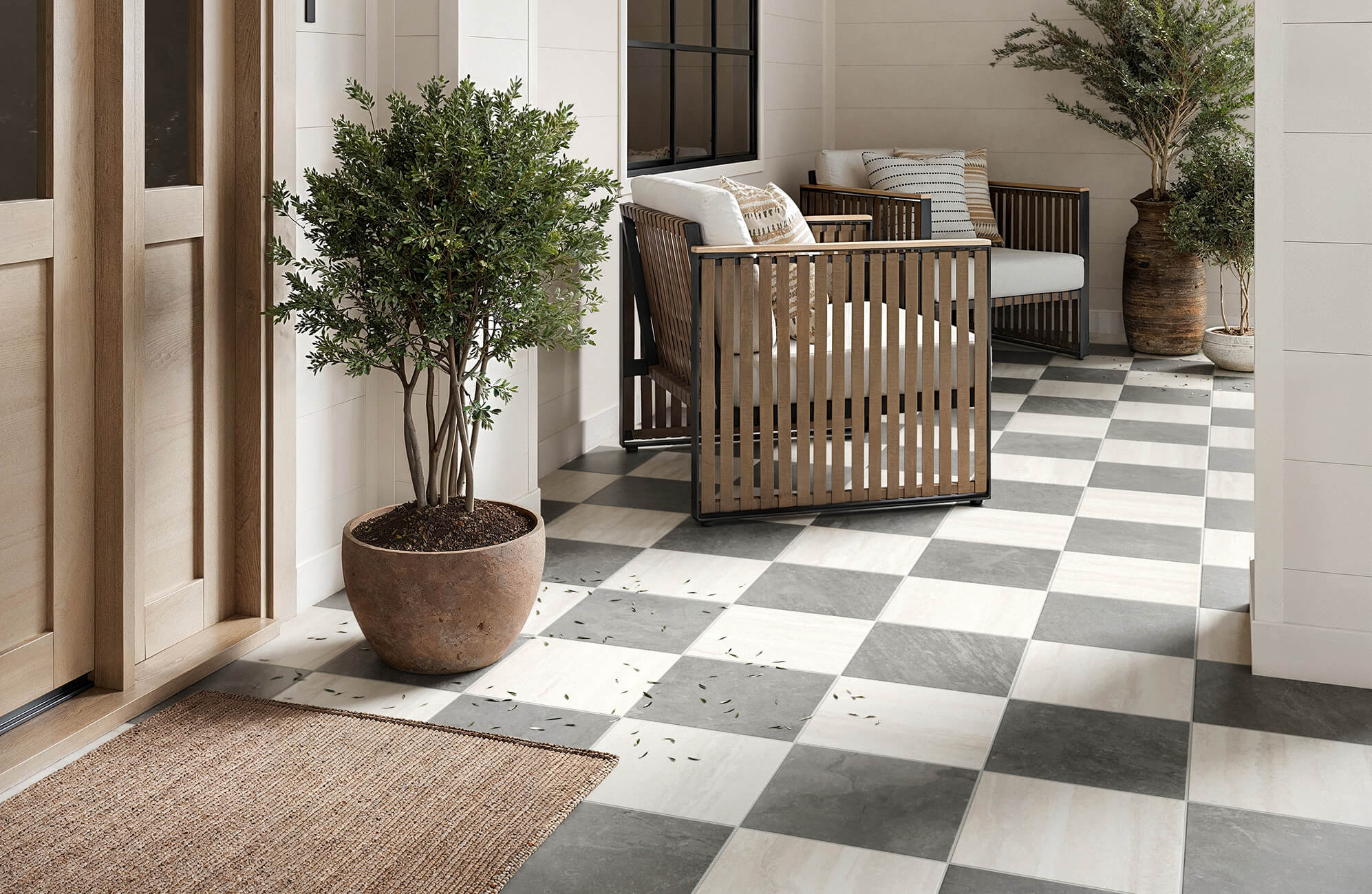 null Inviting porch with grey and ivory checkerboard tiles, featuring modern wood-accent chairs and potted greenery.