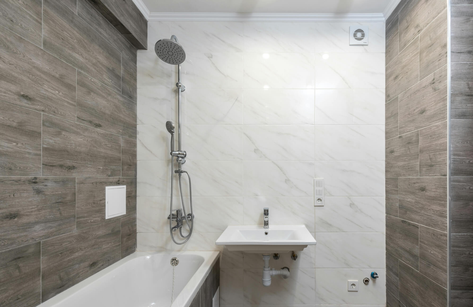 A modern bathroom with peel-and-stick marble wall and wood-look tiles highlighting moisture-resistant surfaces for wet environments.