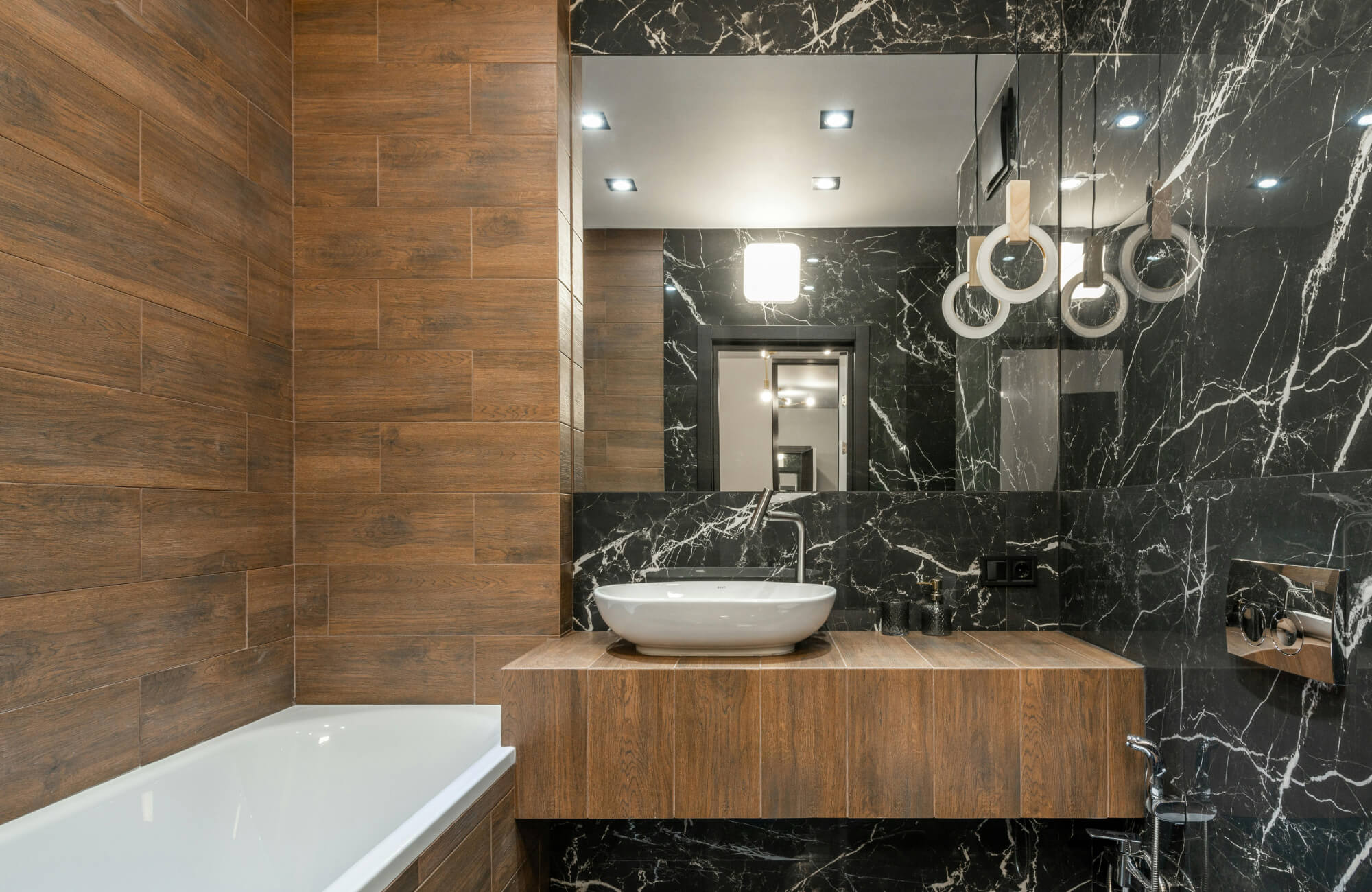 A bathroom combining wood and peel-and-stick black marble tiles demonstrates proper tile placement for durability and style.