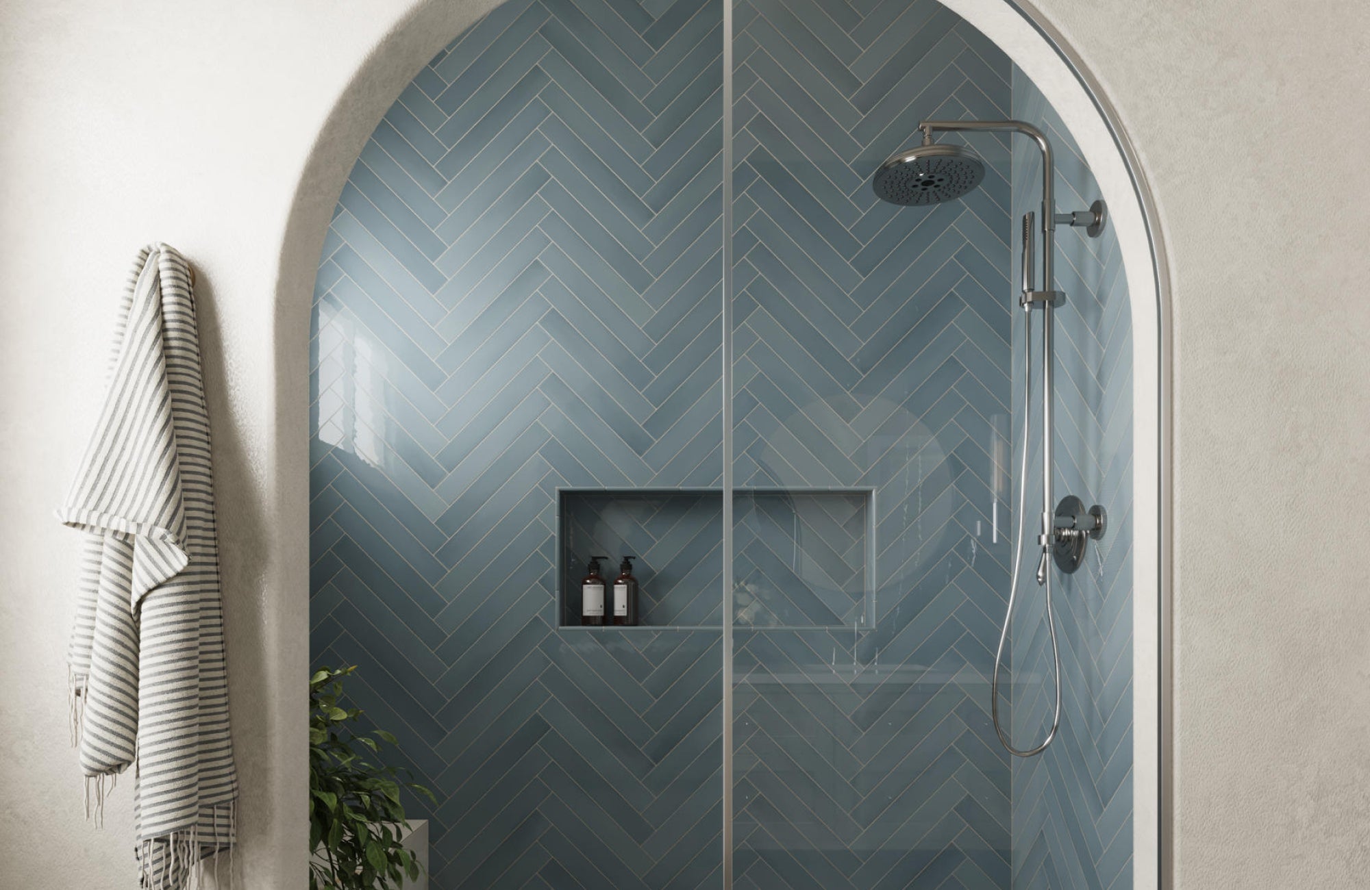 Blue herringbone tile shower with arched entry and glass door, adding movement and timeless charm to the design.