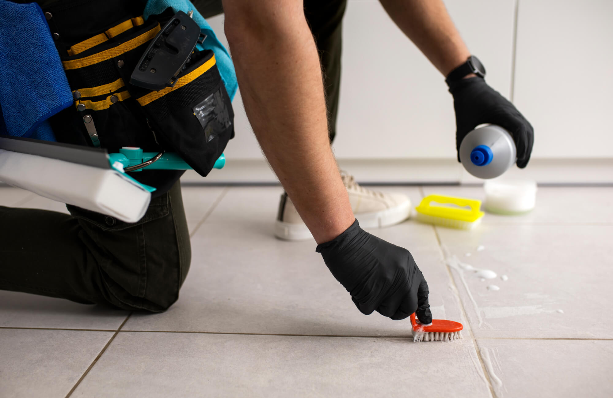 Cleaning and maintaining bathroom floor tiles and grout lines using a brush and solution, highlighting proper bathroom tile maintenance and grout cleaning techniques.