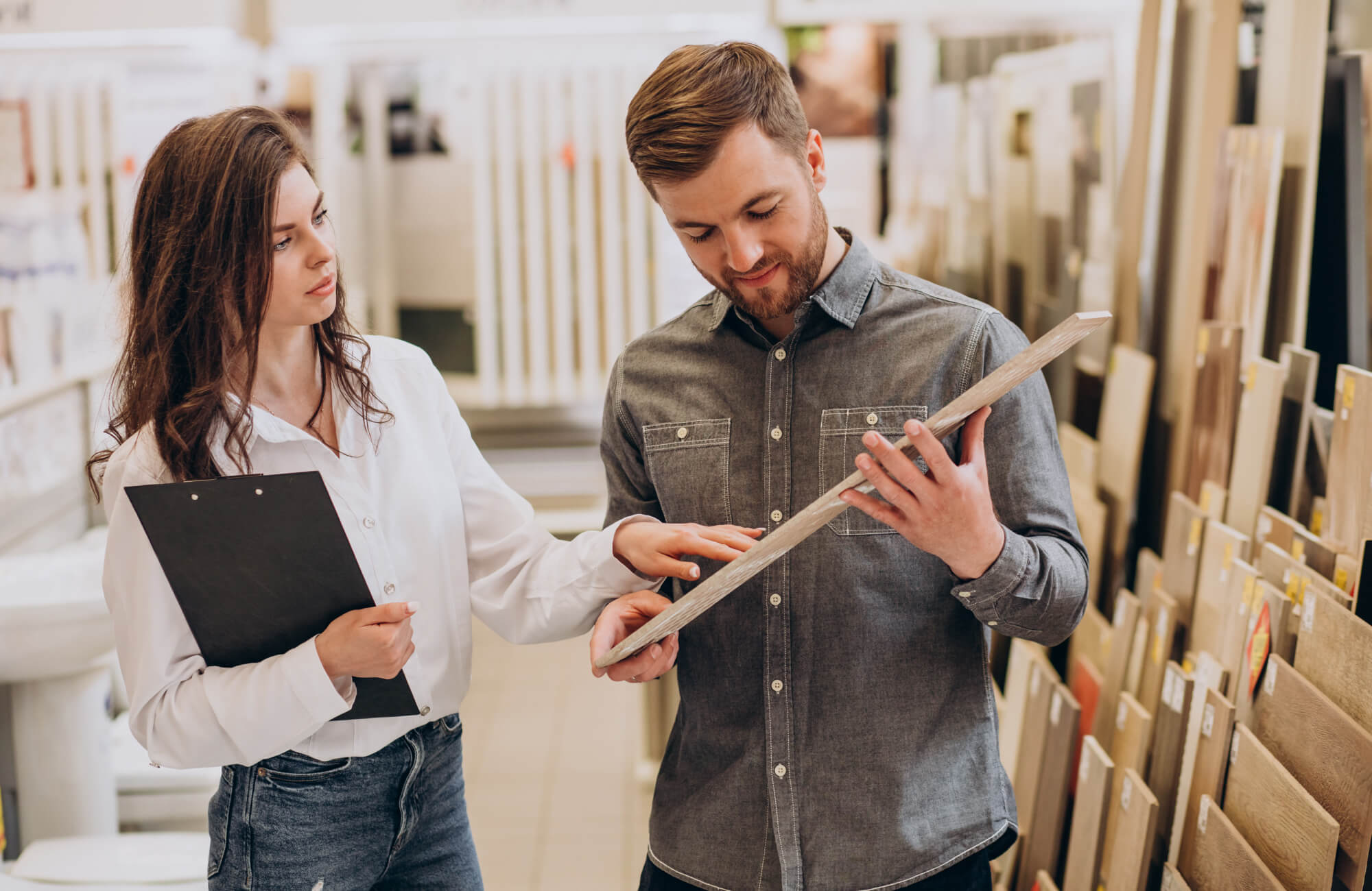 Choosing bathroom tiles in a showroom with expert guidance, comparing porcelain and ceramic bathroom tiles for floor and wall tile selection decisions.