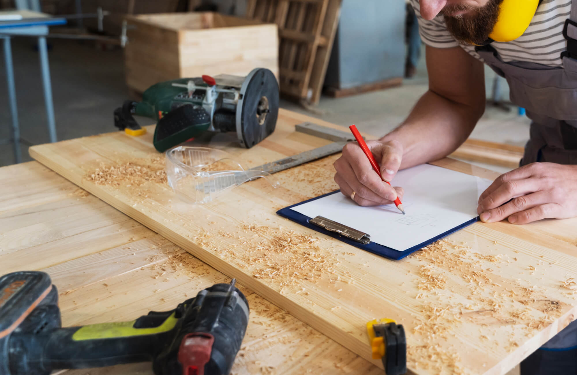 null A contractor carefully sketches measurements on a clipboard beside power tools and fresh wood shavings, emphasizing detailed planning and precision essential to a successful bathroom renovation.