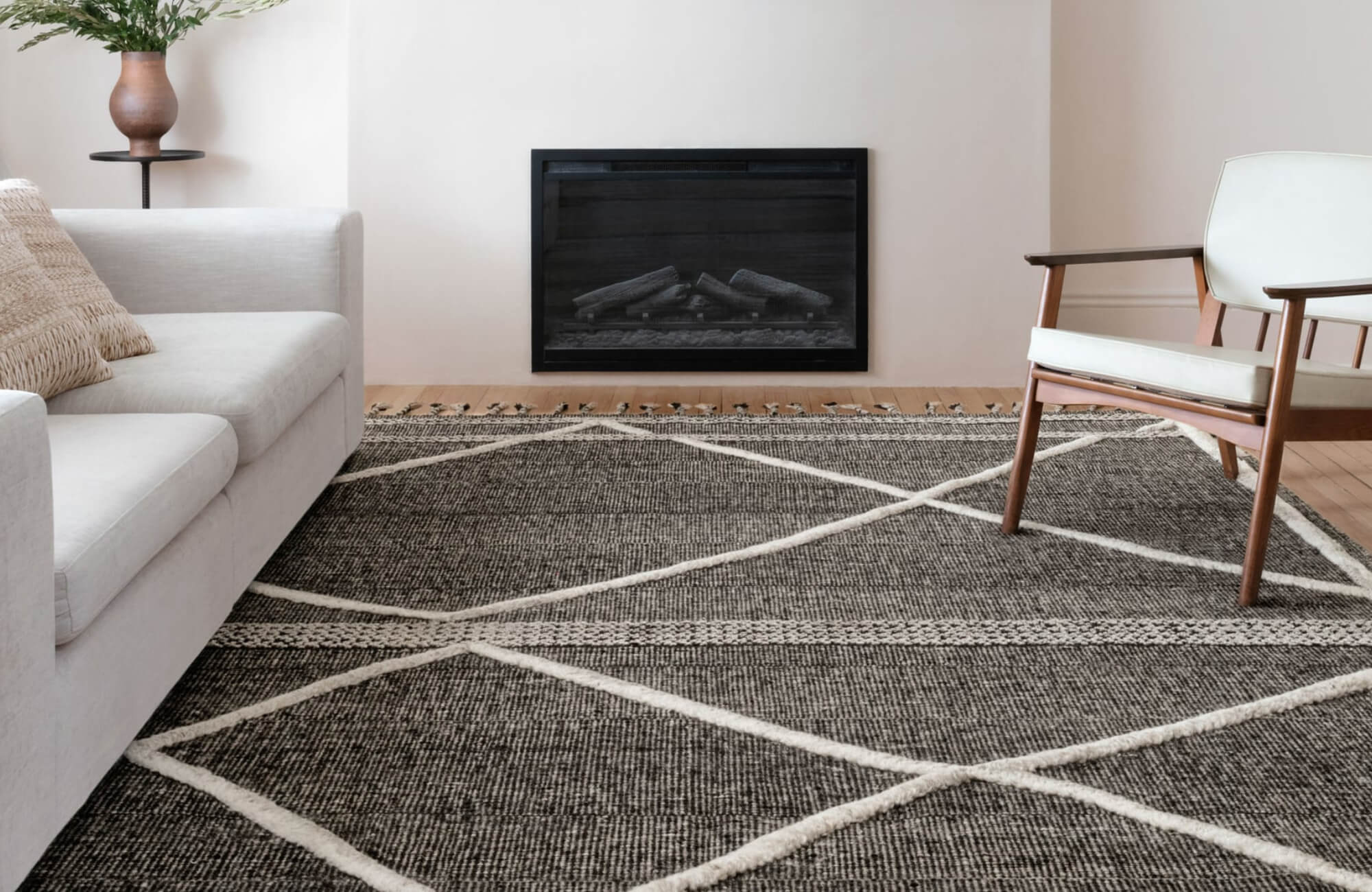 null A dark wool rug with white crisscross lines in a modern living room featuring light furniture and a minimalist fireplace.