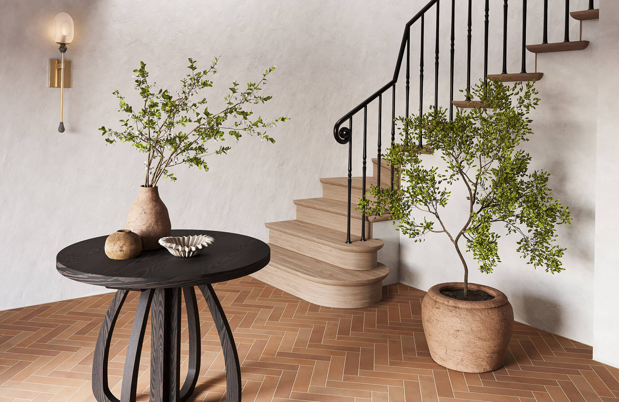 Entryway featuring warm terracotta herringbone tile floors, curved staircase, and potted greenery that adds movement and visual flow.