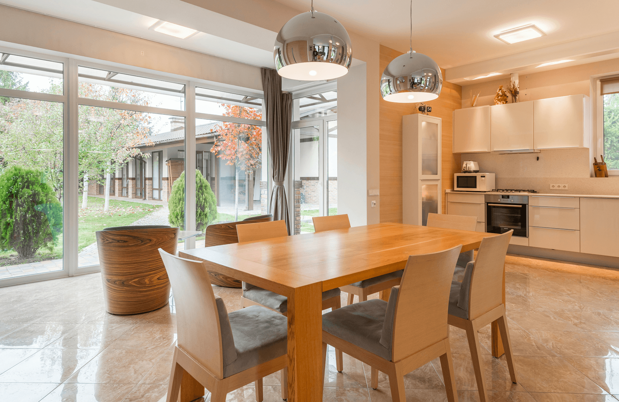null Bright kitchen and dining area with marble flooring, large windows, and wood furniture highlighting durability in everyday living spaces.