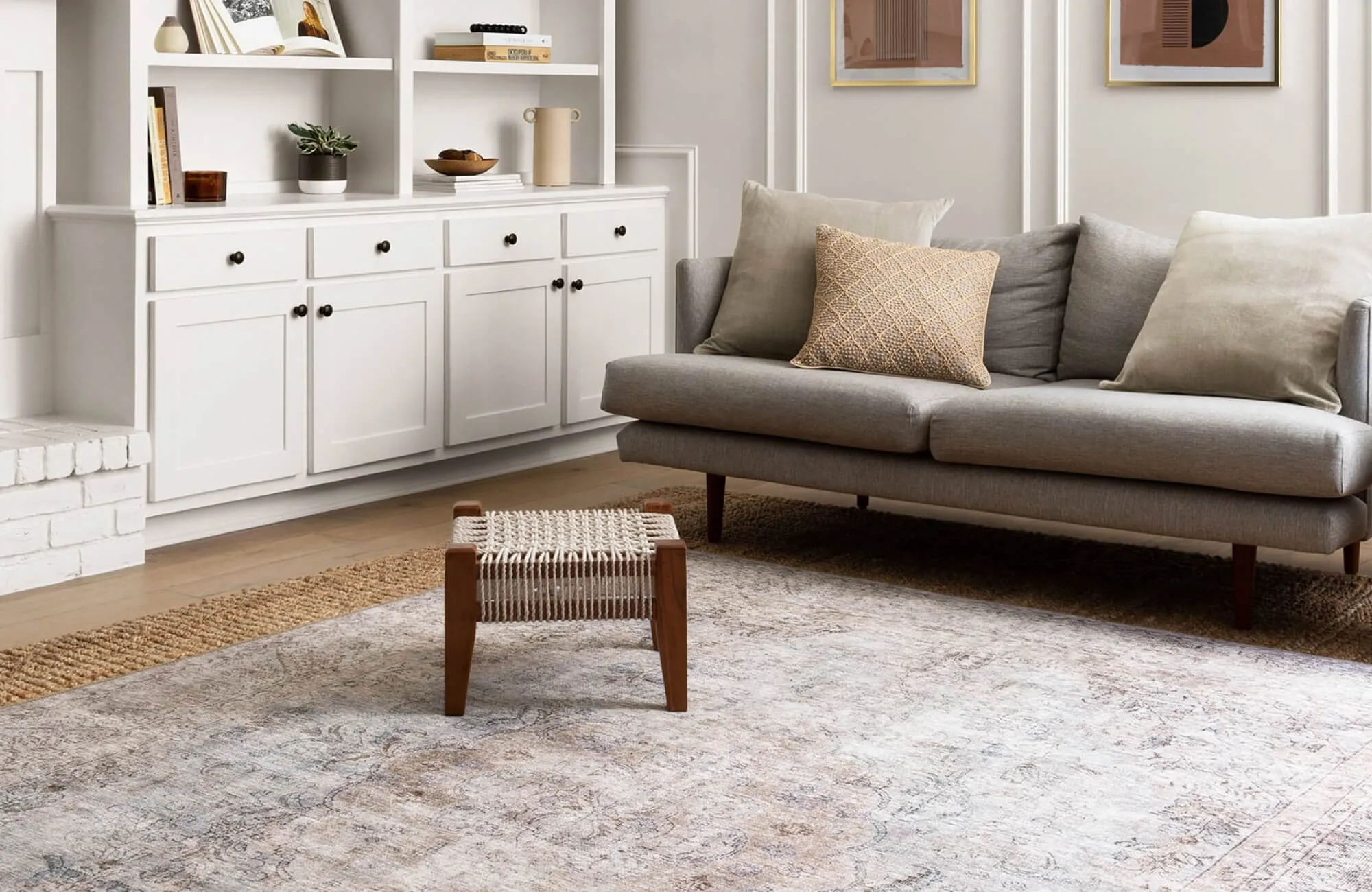 Neutral living room with beige distressed vintage-style area rug, subtle medallion pattern softening modern sofa and built-in shelving.