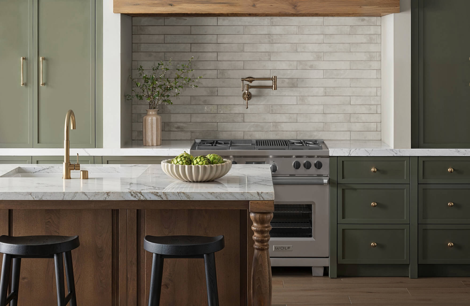 null Modern kitchen with sage green cabinets, marble countertops, and light gray subway tile backsplash accented by brass fixtures.