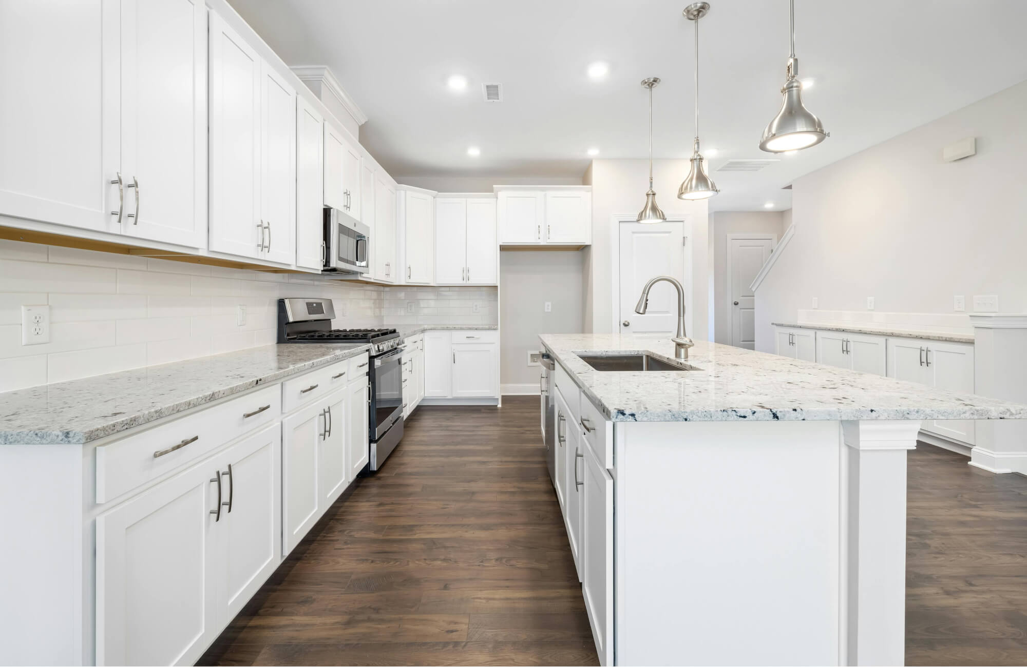 null Spacious white galley kitchen featuring pendant lighting, long counters, and ample cabinetry along both sides.