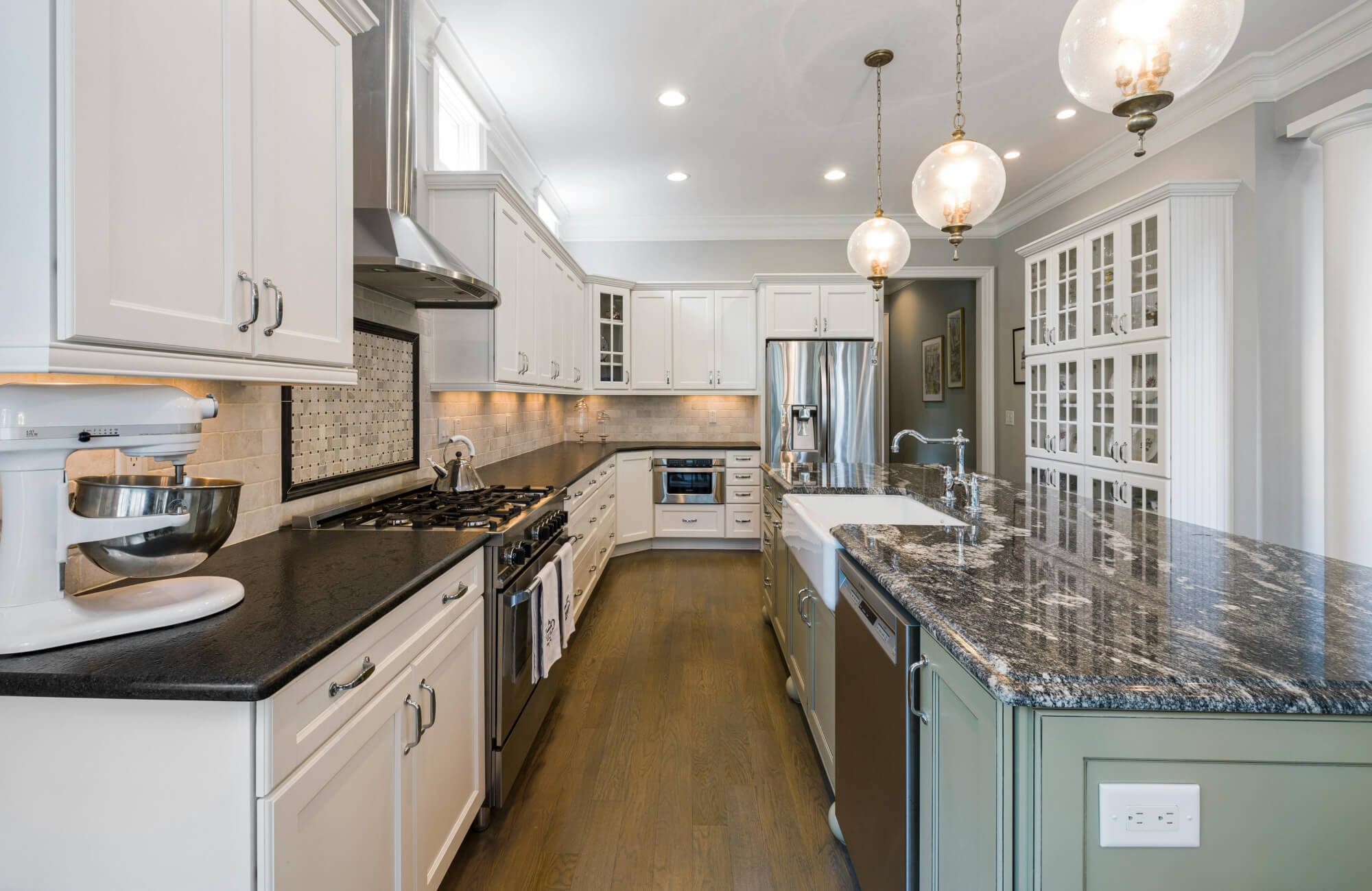 null Elegant galley kitchen with globe pendants, dark counters, and detailed cabinetry creating a refined narrow workspace.