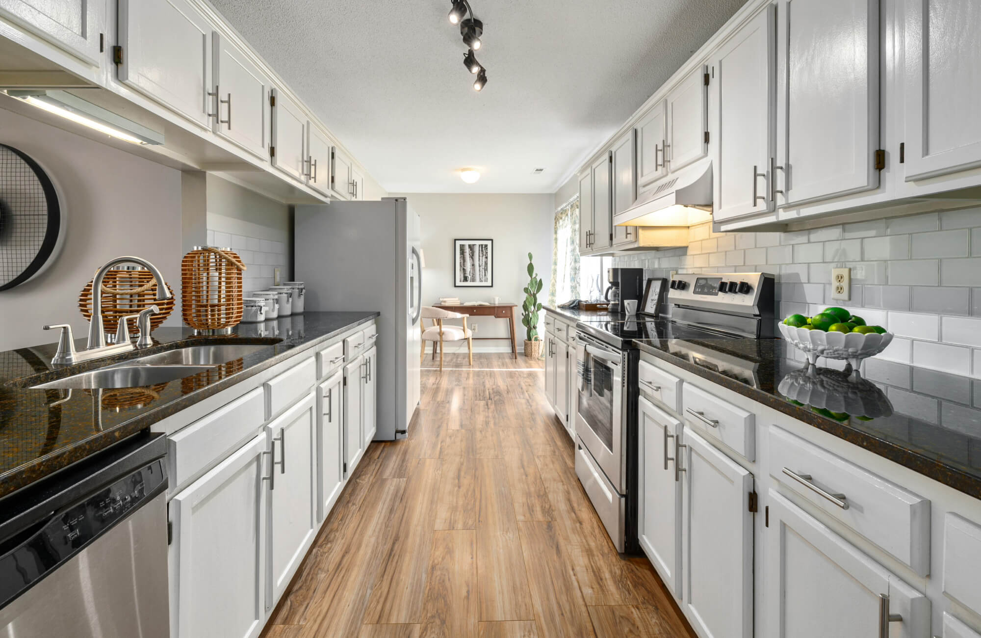null Classic galley kitchen with white cabinets, track lighting, and dark countertops extending along both sides of the corridor.