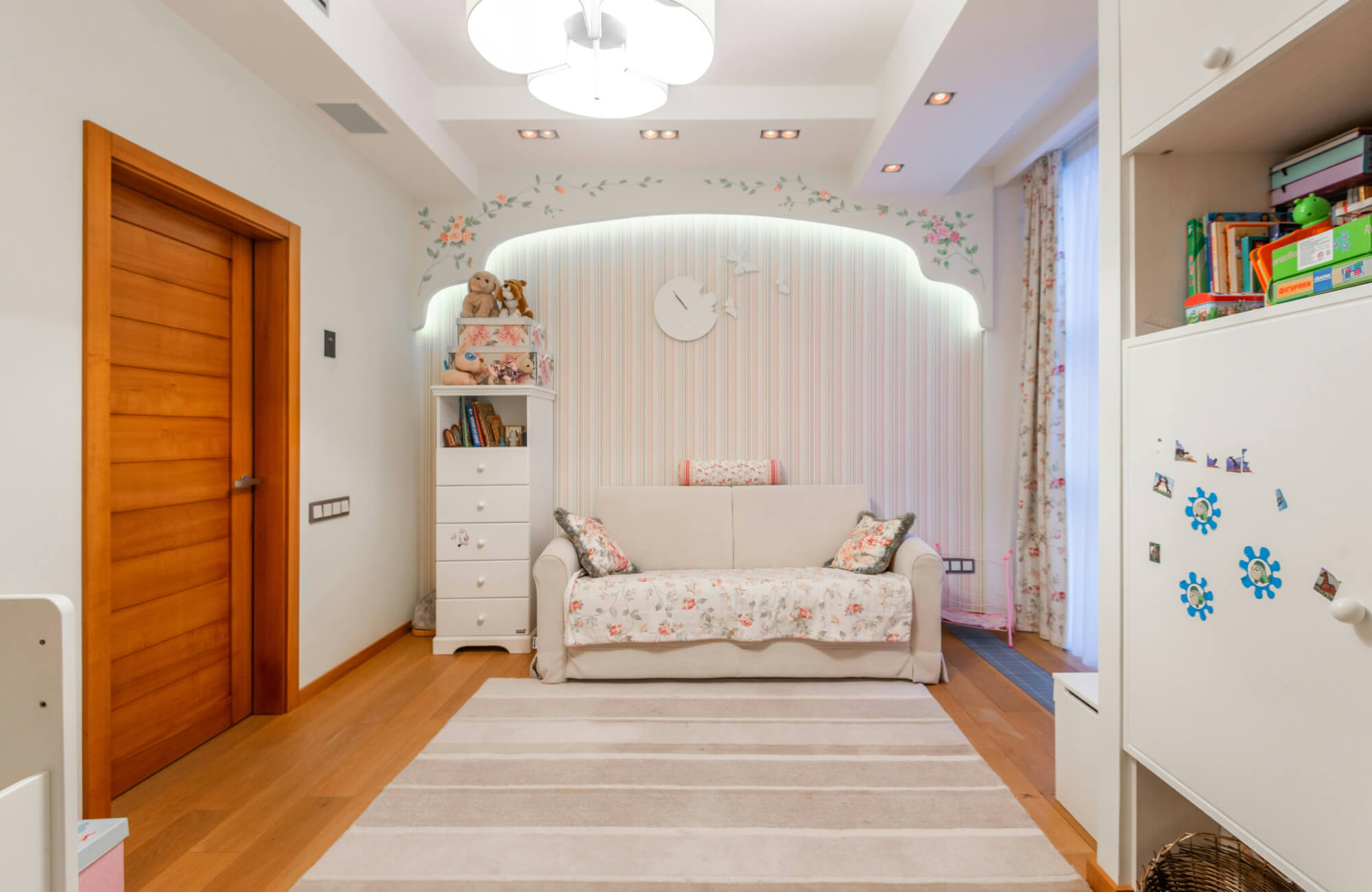 Neutral striped rug placed in front of a nursery sofa, sized to fit the open floor area without blocking doors or storage