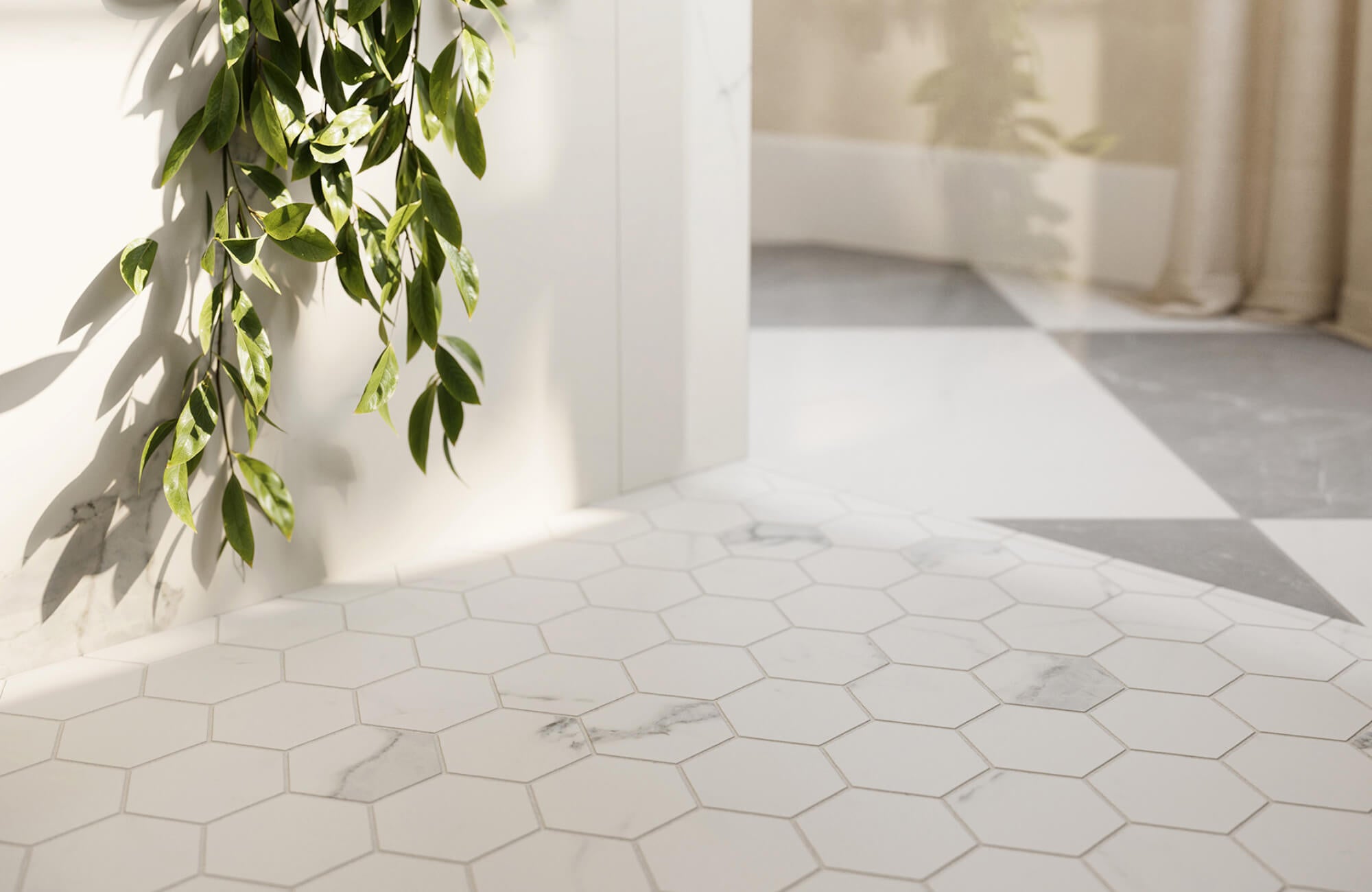Close-up of white marble hexagon floor tiles with subtle veining, natural light, and green foliage creating a soft, modern bathroom detail.