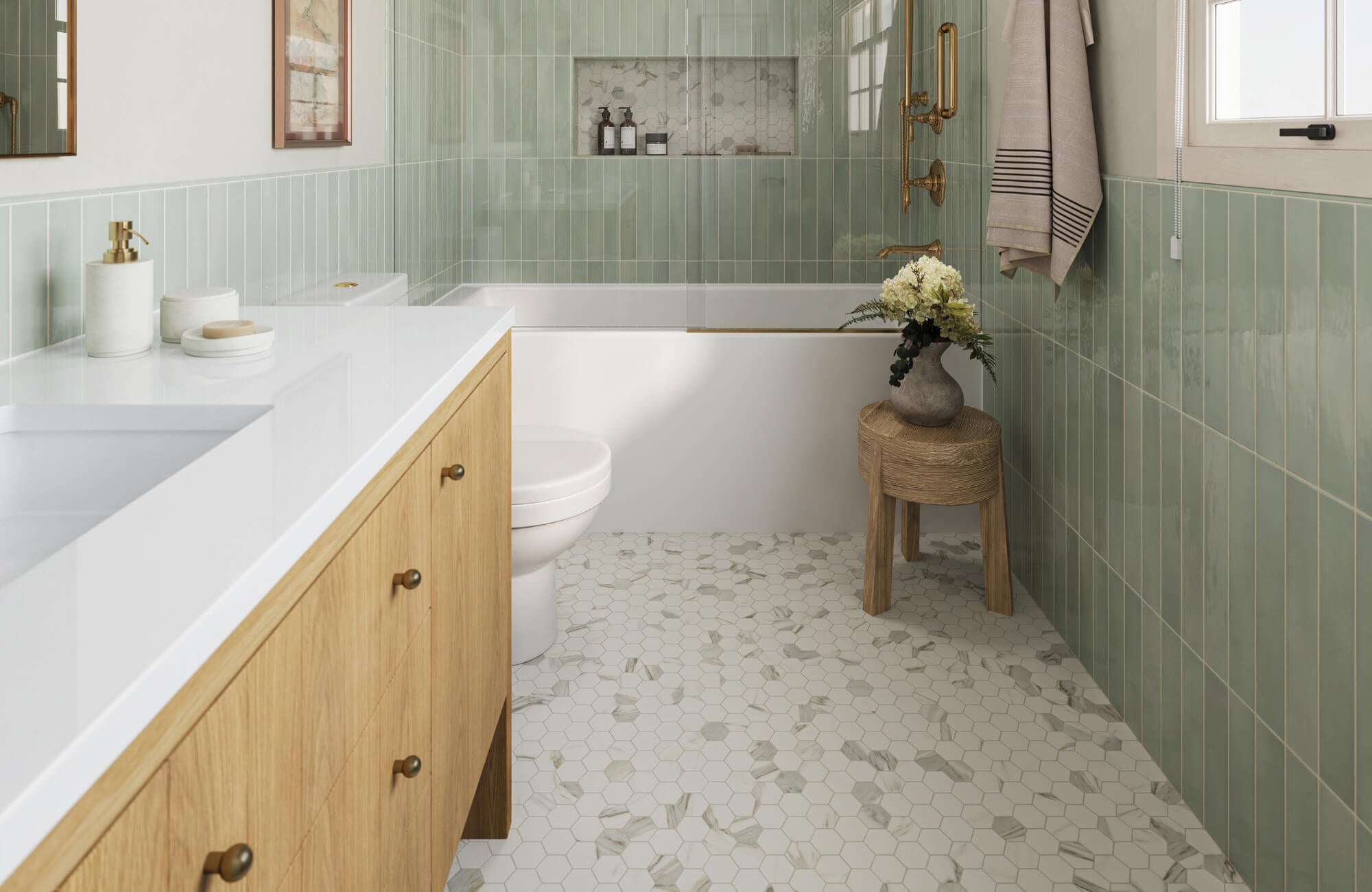 Bright bathroom with light wood vanity, green vertical wall tiles, white bathtub, and marble hexagon floor tiles accented with subtle veining.