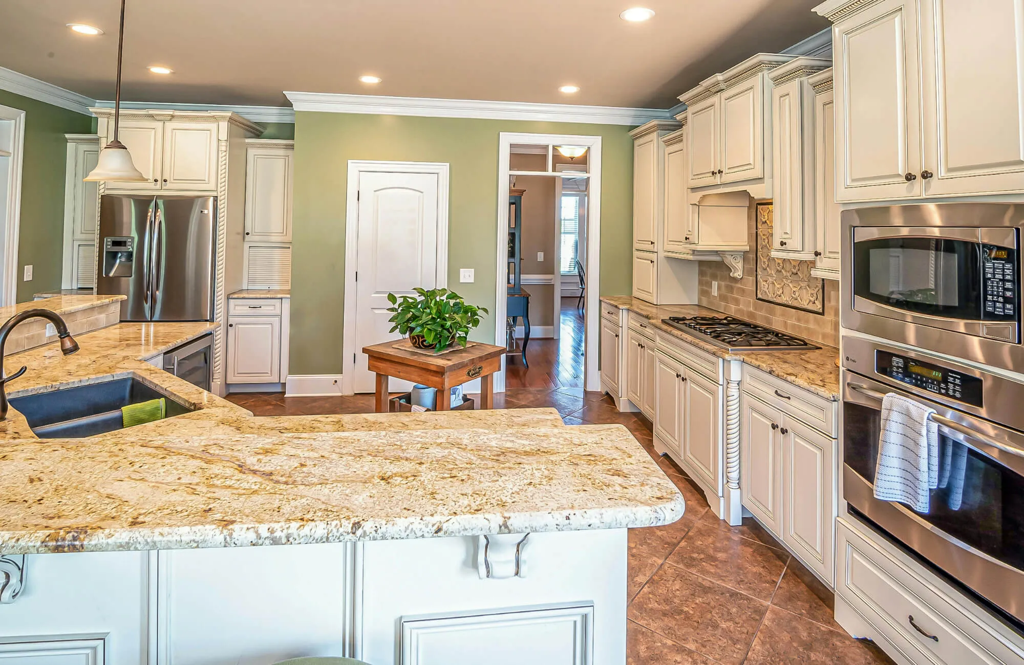 Bright traditional kitchen with cream cabinets, granite countertops, stainless steel appliances, and a tile backsplash accent.