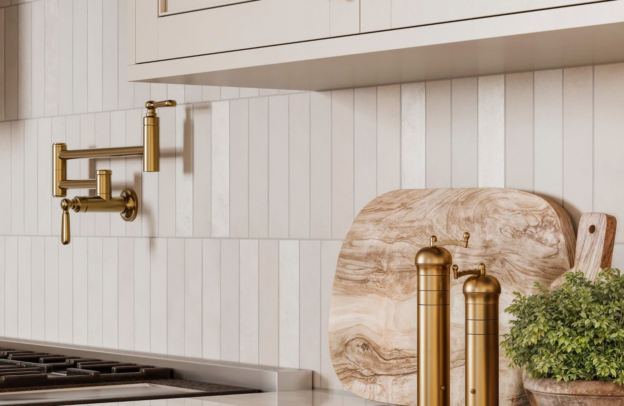 Modern kitchen backsplash with vertical neutral tiles, brass pot filler, wood cutting boards, and fresh herbs on a marble countertop.