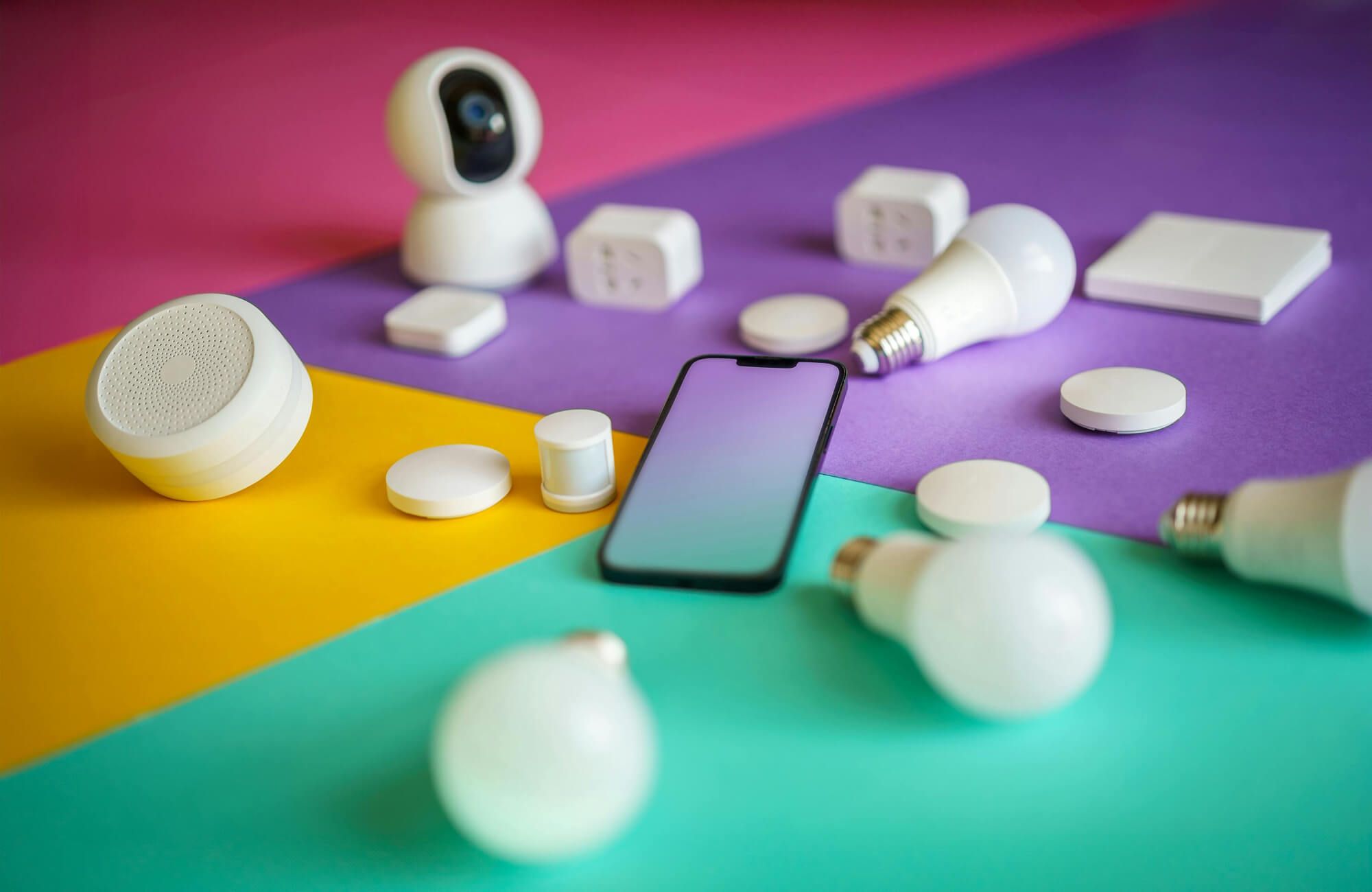 null Smart lighting and home automation devices with a smartphone, including bulbs, plugs, and sensors, arranged on a colorful background.