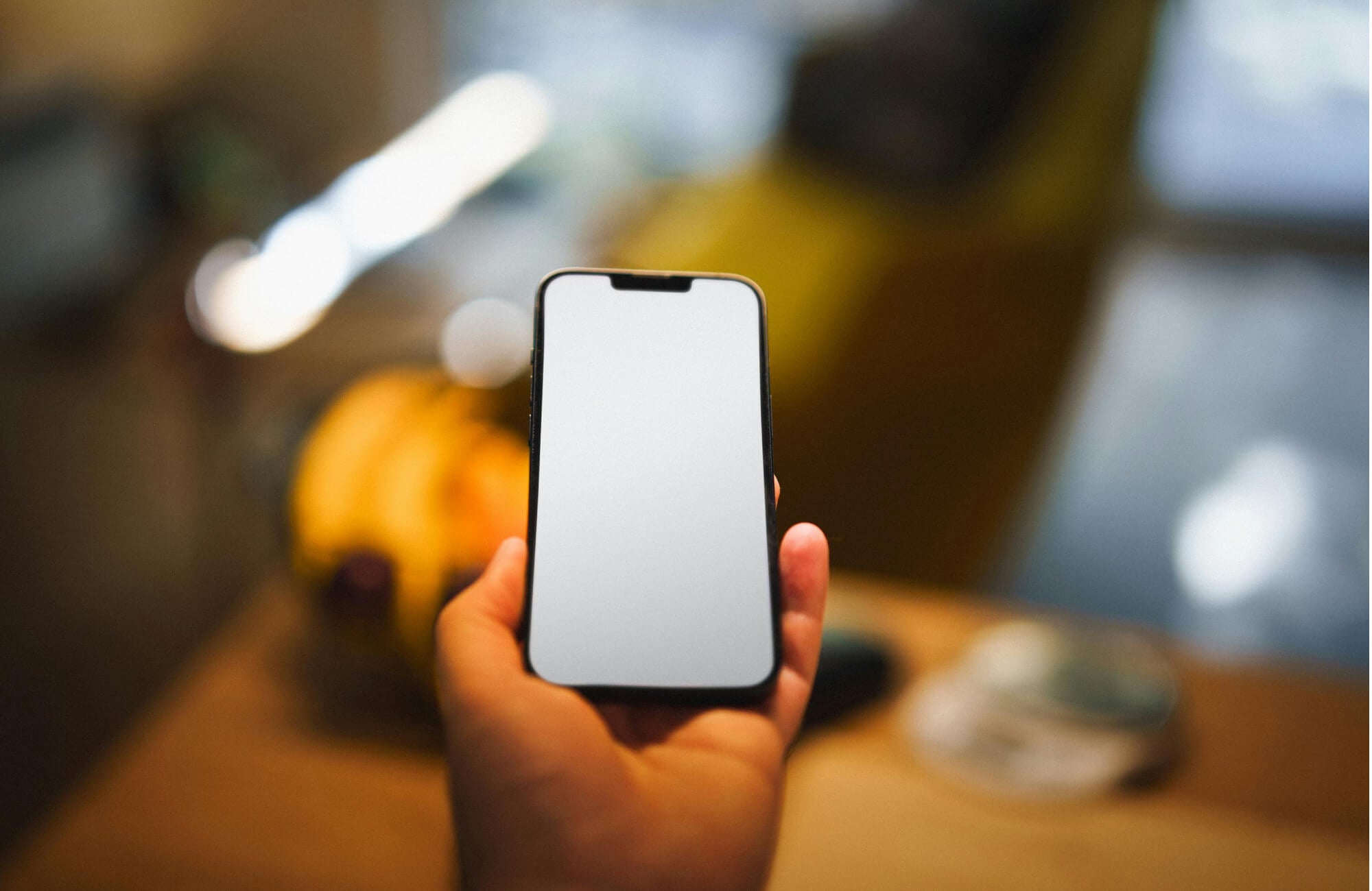 null Hand holding a smartphone with a blank screen, ready to control smart lighting or connected devices at home.