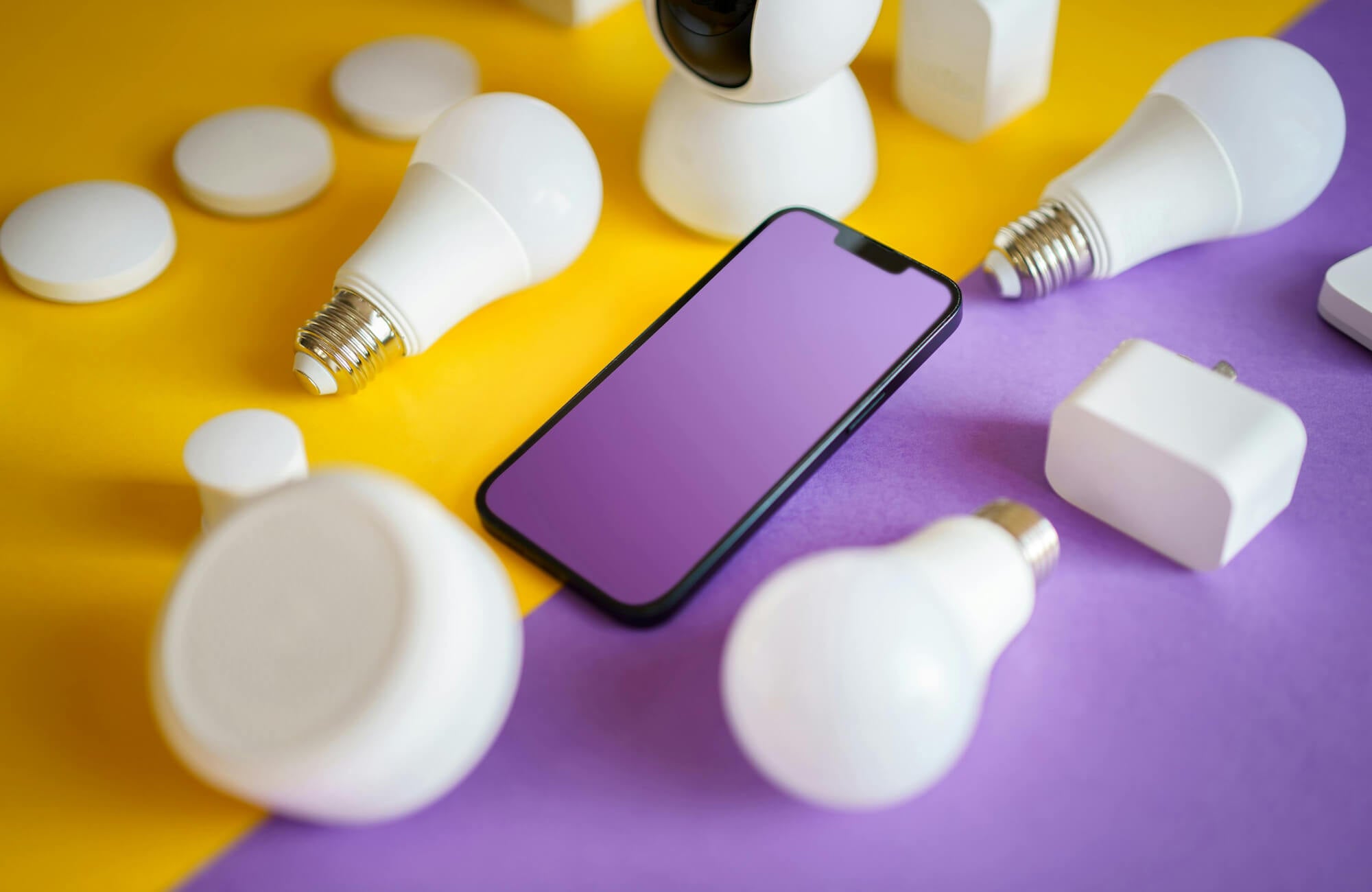 null Close-up of smart home devices, including LED bulbs, plugs, and a phone, representing mobile control of modern lighting systems.