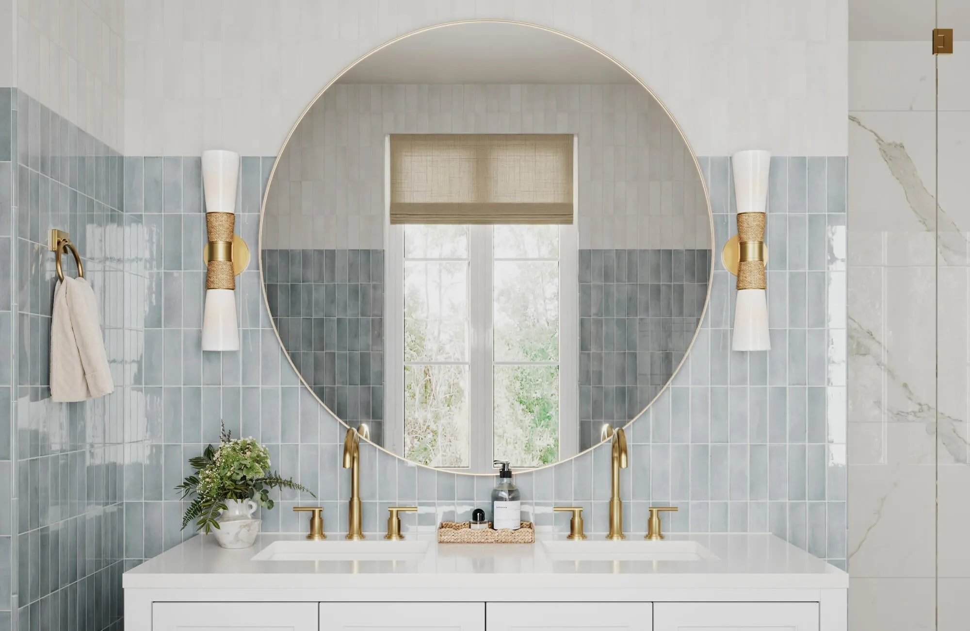 Elegant bathroom with vertical blue zellige tiles, oversized round mirror, gold double faucets, and white-and-gold bowtie sconces.