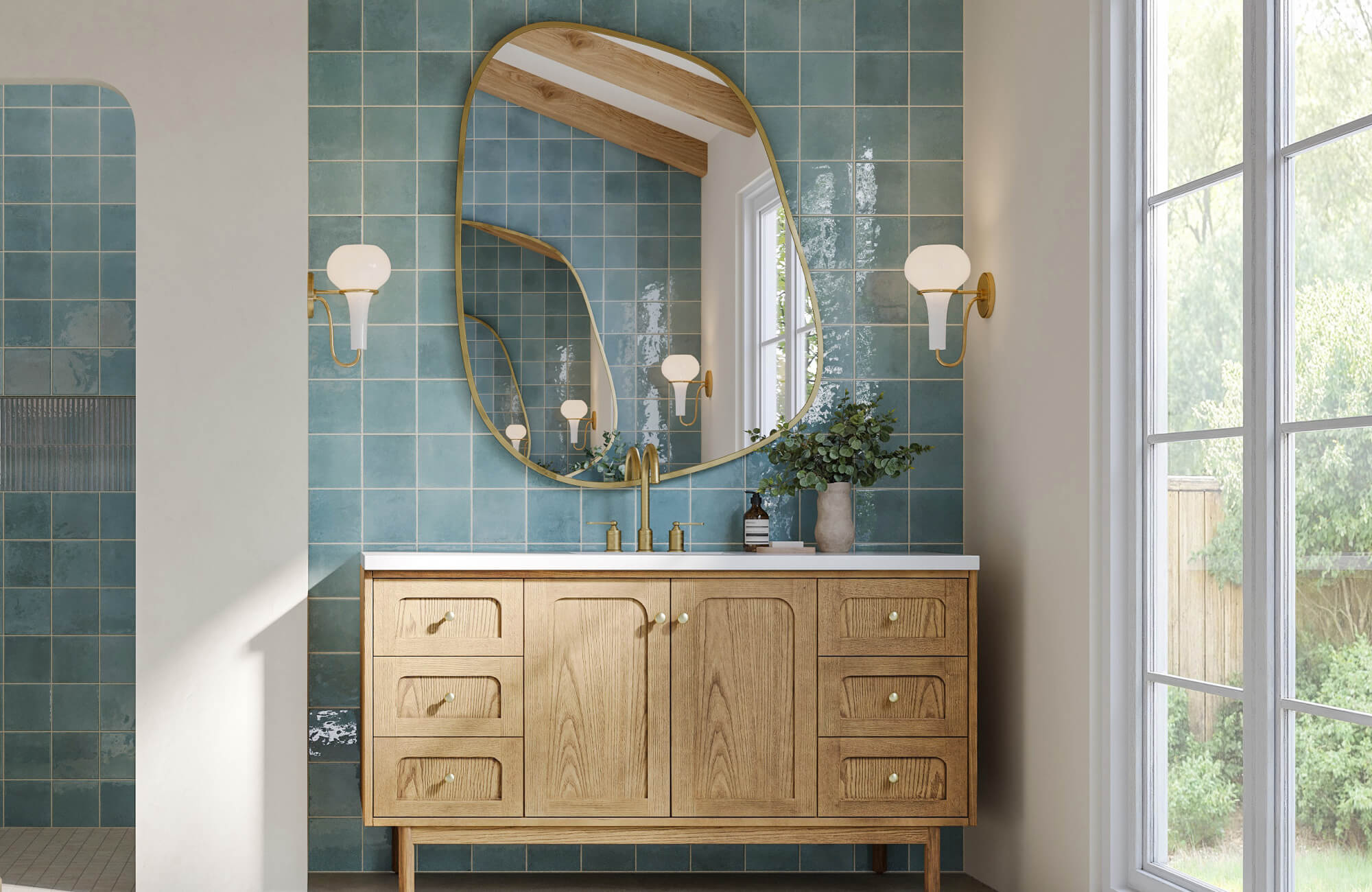 Bathroom with handcrafted teal square tiles, organic brass mirror, and a natural wood vanity beneath modern sconces.