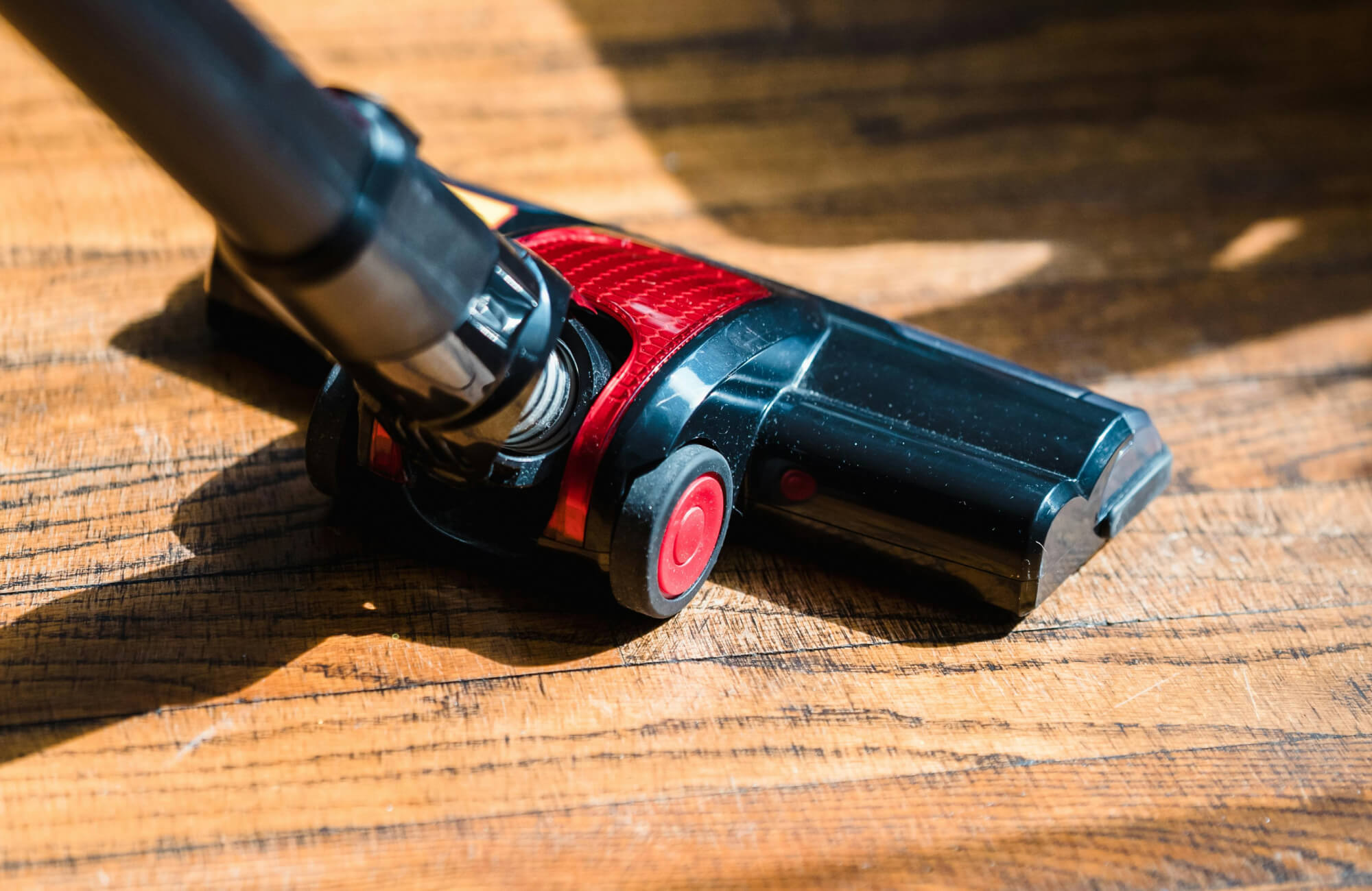 null Vacuum cleaning debris from a wood floor to prevent scratches and maintain the protective finish of the kitchen wood flooring.