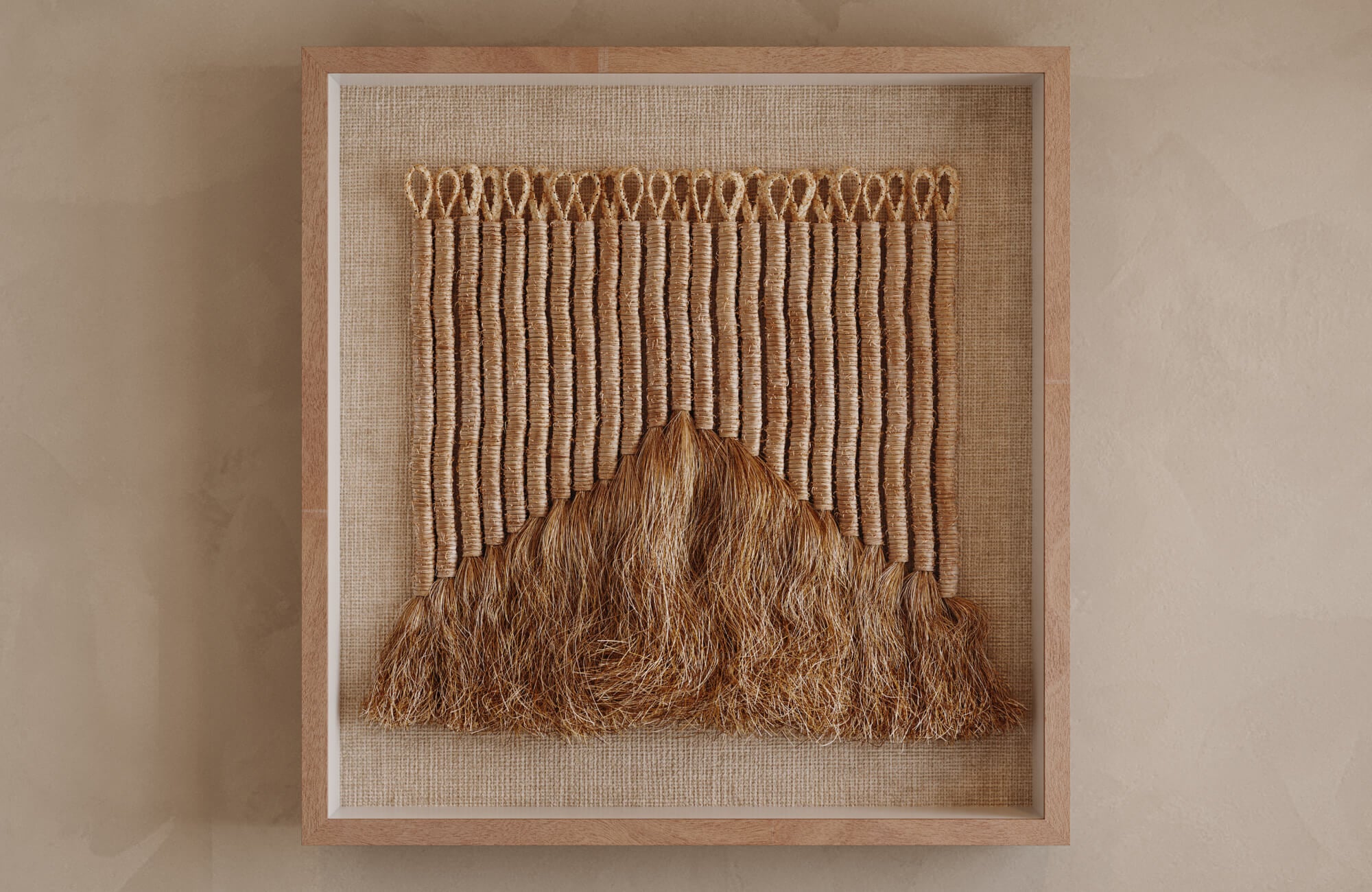 Large square wall art in light oak frame with beige fabric backing and tan woven fiber detail, showing how texture and scale create presence on taller walls.
