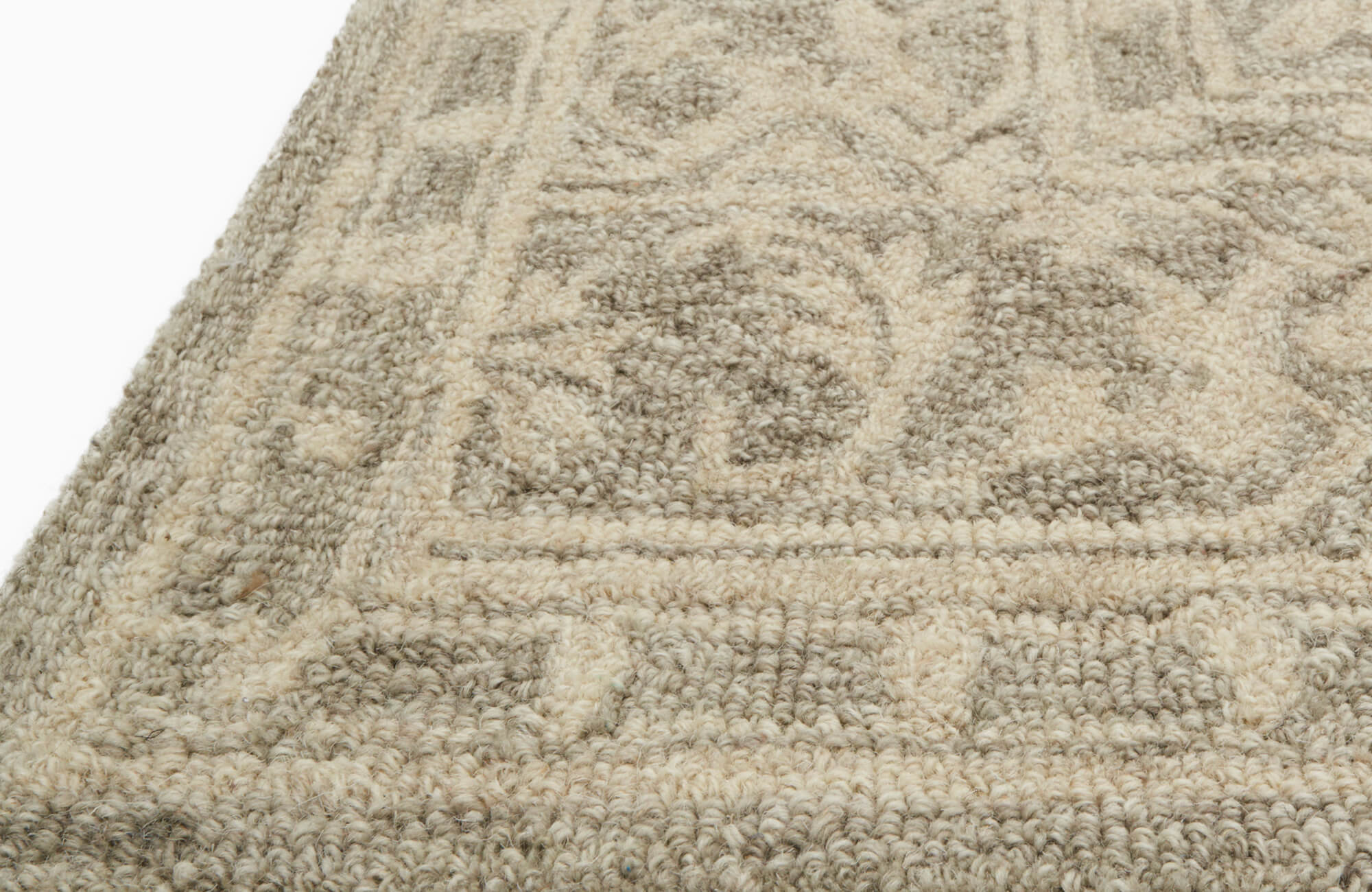 null Close-up of a loop-pile wool rug with a raised geometric pattern in warm beige tones.