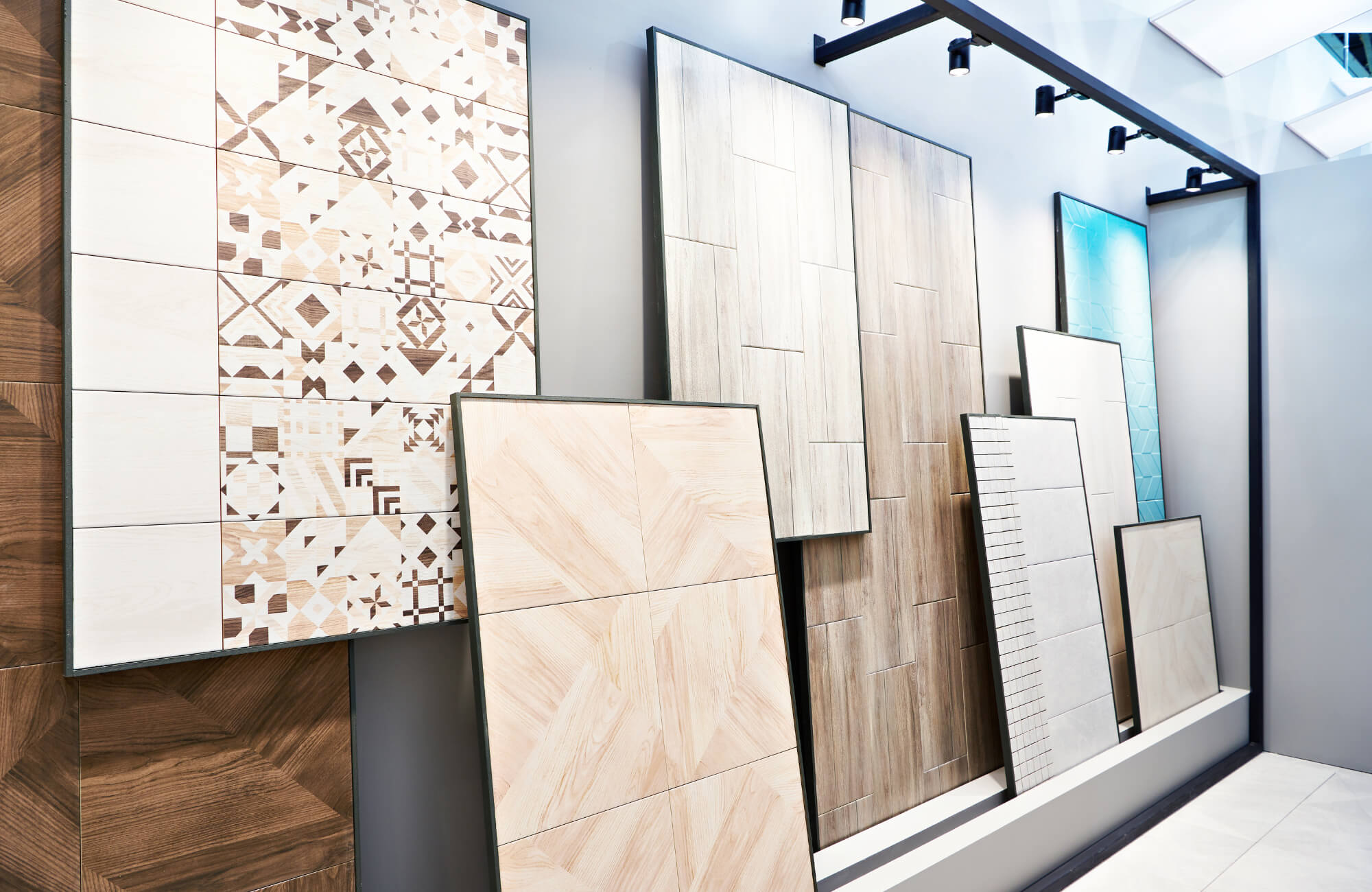 null Display of assorted wood look and patterned ceramic tiles in a showroom, showcasing various colors, textures, and installation styles.