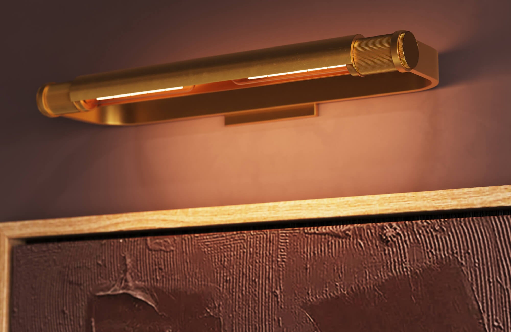 Close-up of a sleek brass picture light casting a warm glow over textured burgundy artwork in a natural wood frame.
