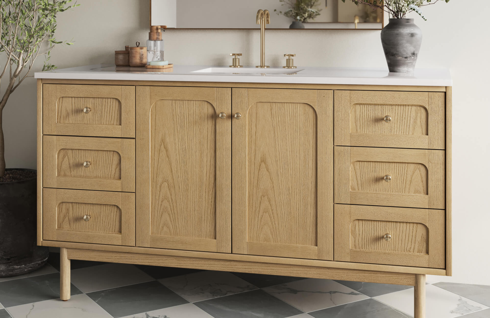 Light oak vanity with arched panel detailing, brass fixtures, and a white countertop for a soft, modern vintage aesthetic.