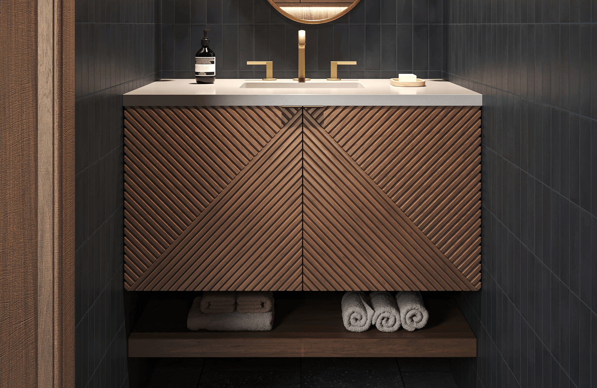 Compact vanity with rich wood chevron paneling, brass faucet, and white top set against sleek dark vertical tile walls.