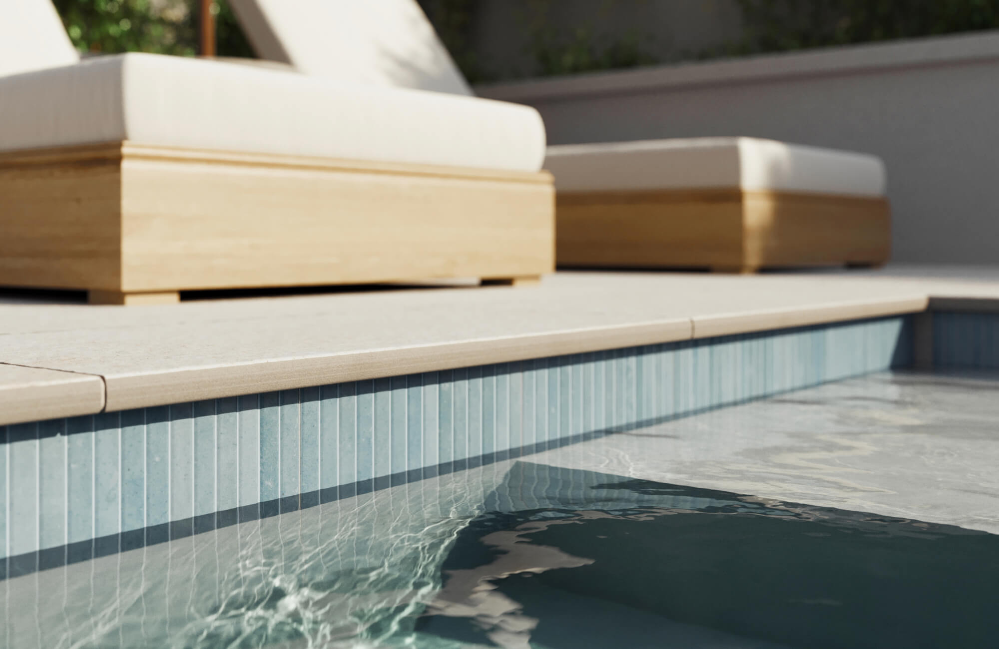 Elegant poolside detail featuring soft blue vertical porcelain tile along the waterline, paired with sleek stone coping.