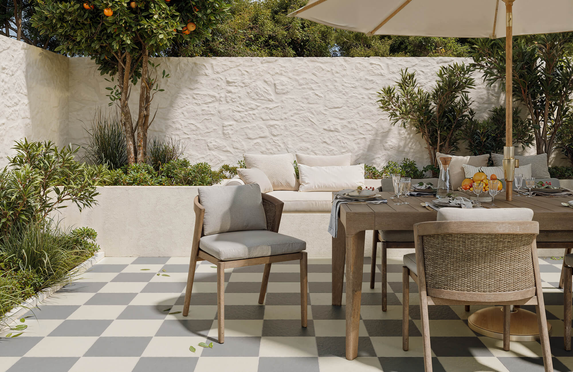 Charming outdoor dining area with soft gray and cream checkerboard porcelain tile flooring under a patio umbrella.