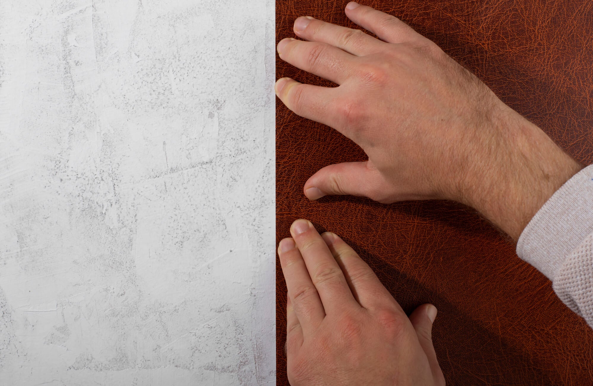 null Peel and stick wallpaper with brown leather-look texture being smoothed onto a white wall during installation.