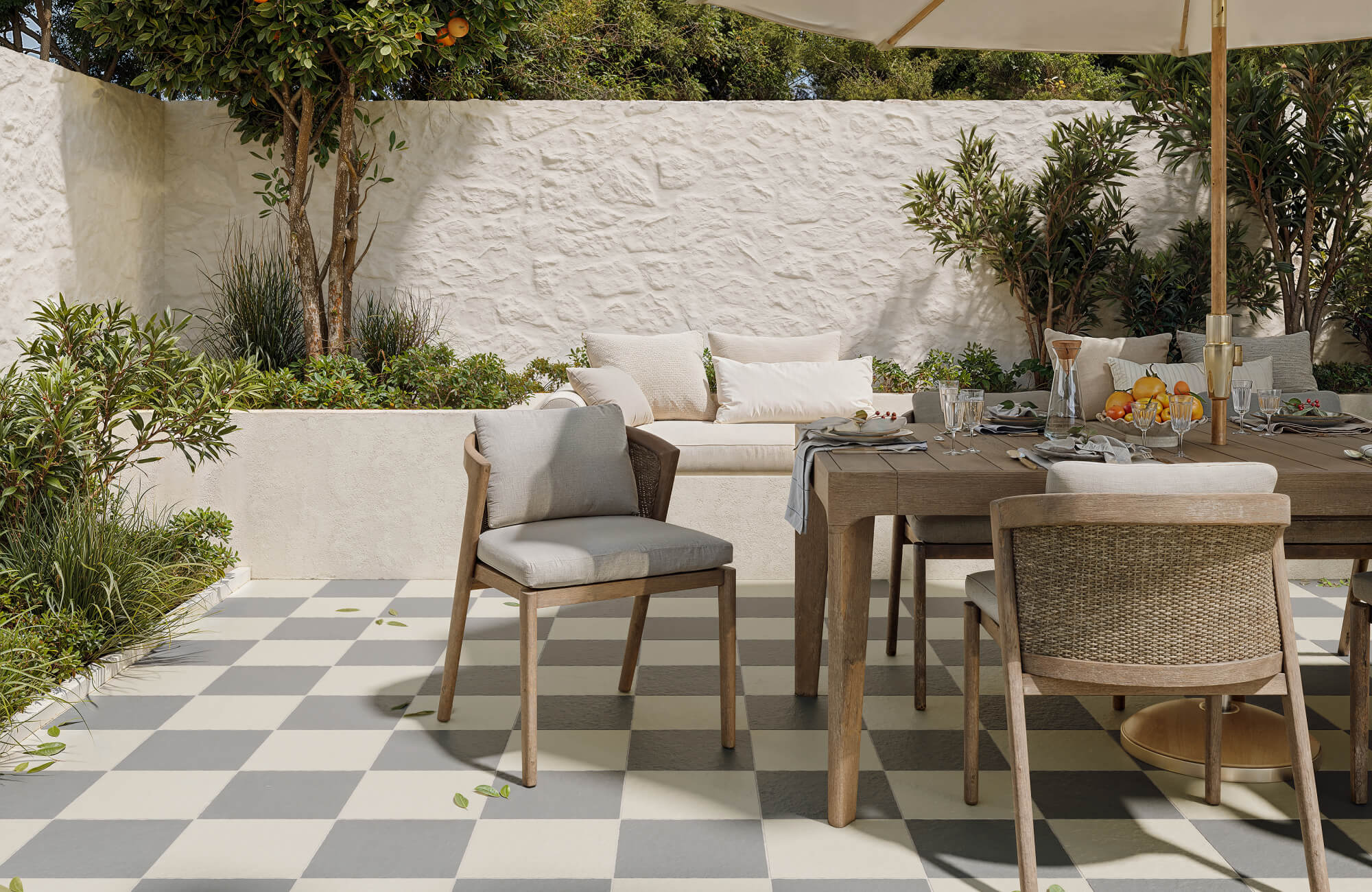 null Outdoor checkerboard tiles in soft gray and cream add playful elegance to this sunlit patio dining area framed by lush greenery.