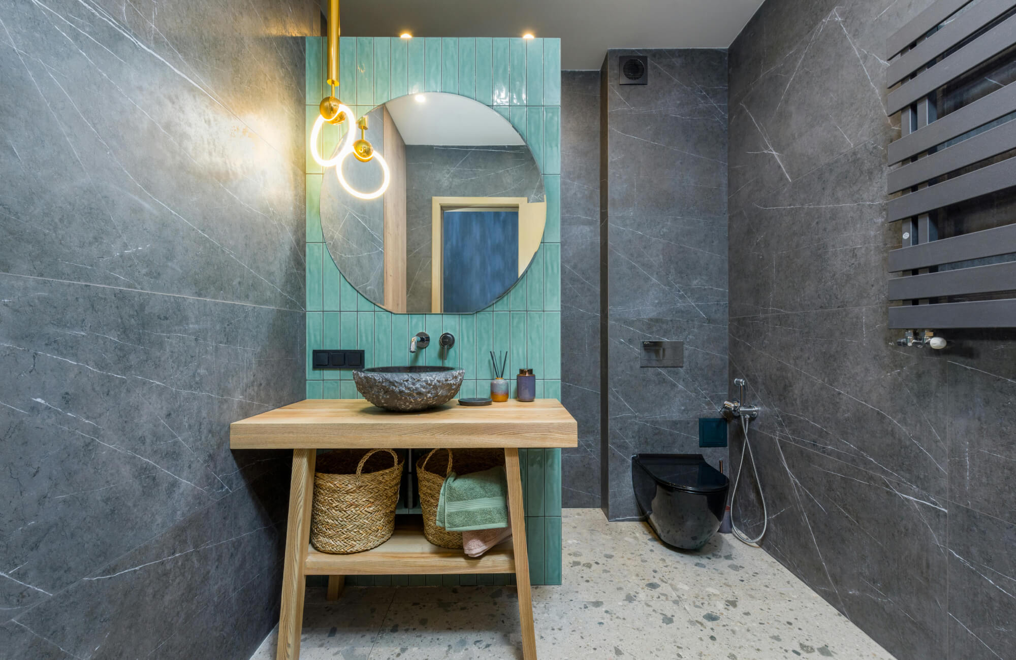 Modern vanity with one overhead pendant light above the round mirror, providing focused illumination in a dark-toned space.