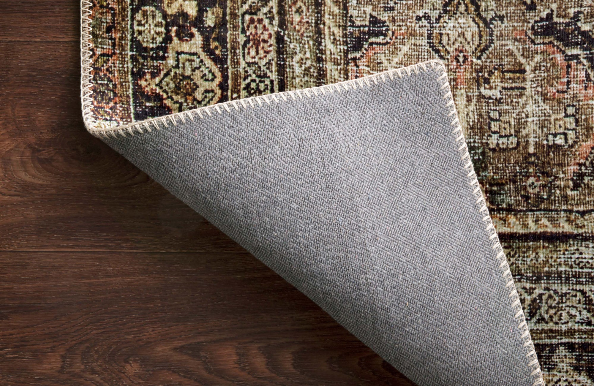 null Close-up of a rug corner flipped to reveal its backing and stitching, highlighting construction and care details.