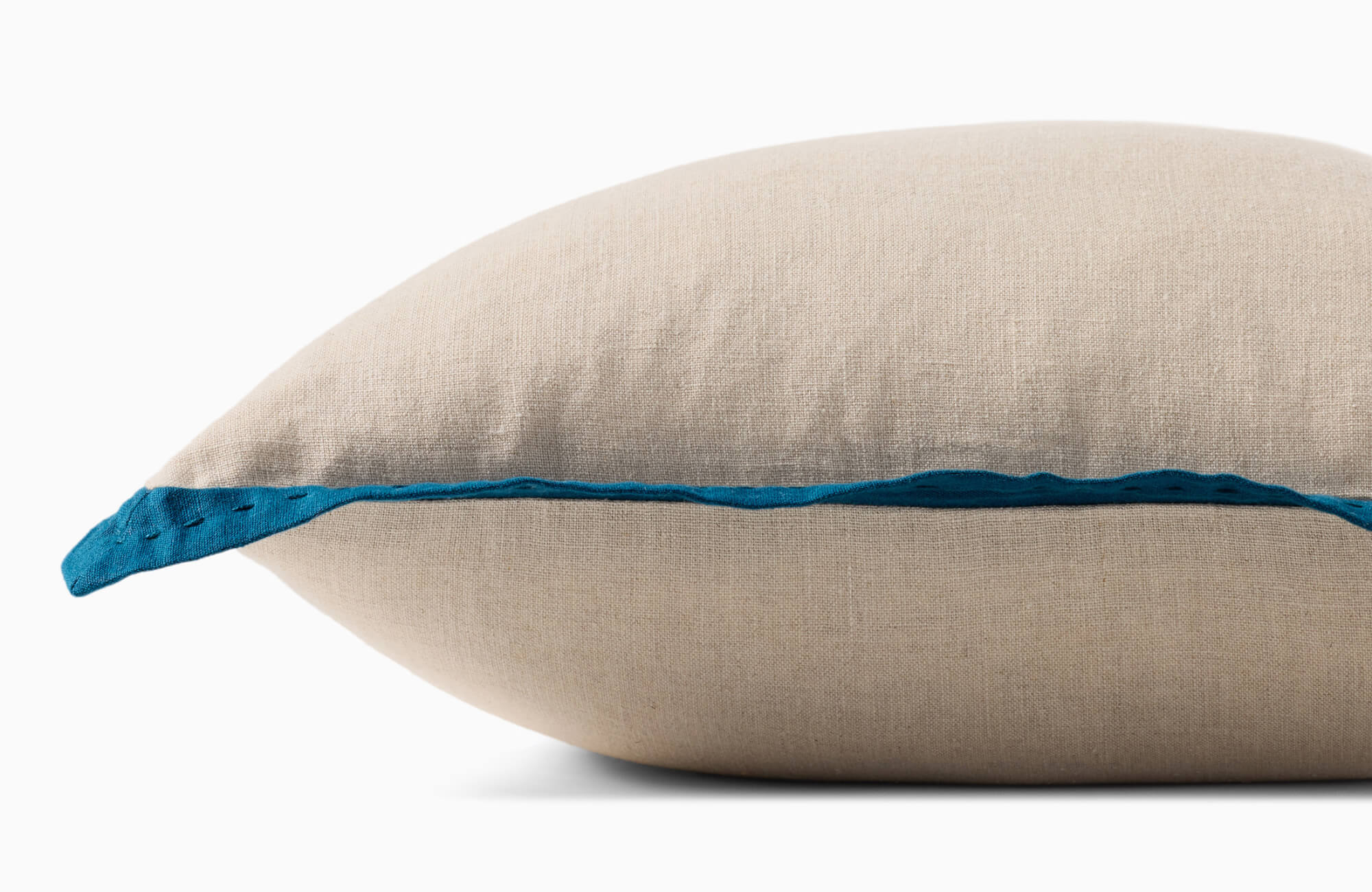 Beige linen decorative pillow with blue contrast edge trim and soft curved silhouette on a gray backdrop.
