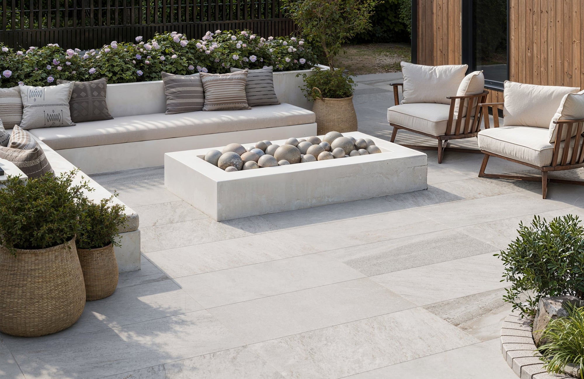Outdoor porcelain tiles in a stylish patio, showcasing light-toned, large-format pavers set around seating and planters for a clean, elegant finish.