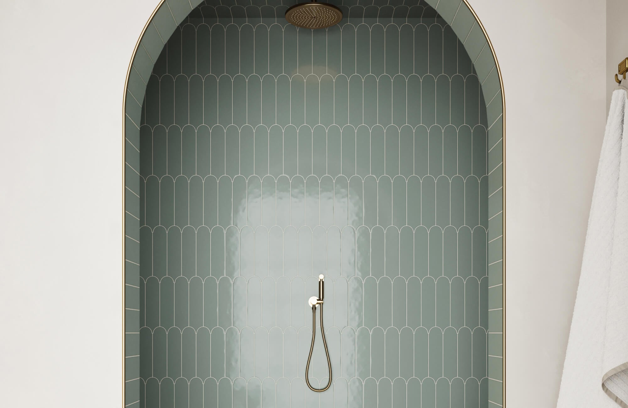 Curved shower alcove with glossy sage green scallop tiles, brass rain showerhead, and minimalist handheld sprayer.