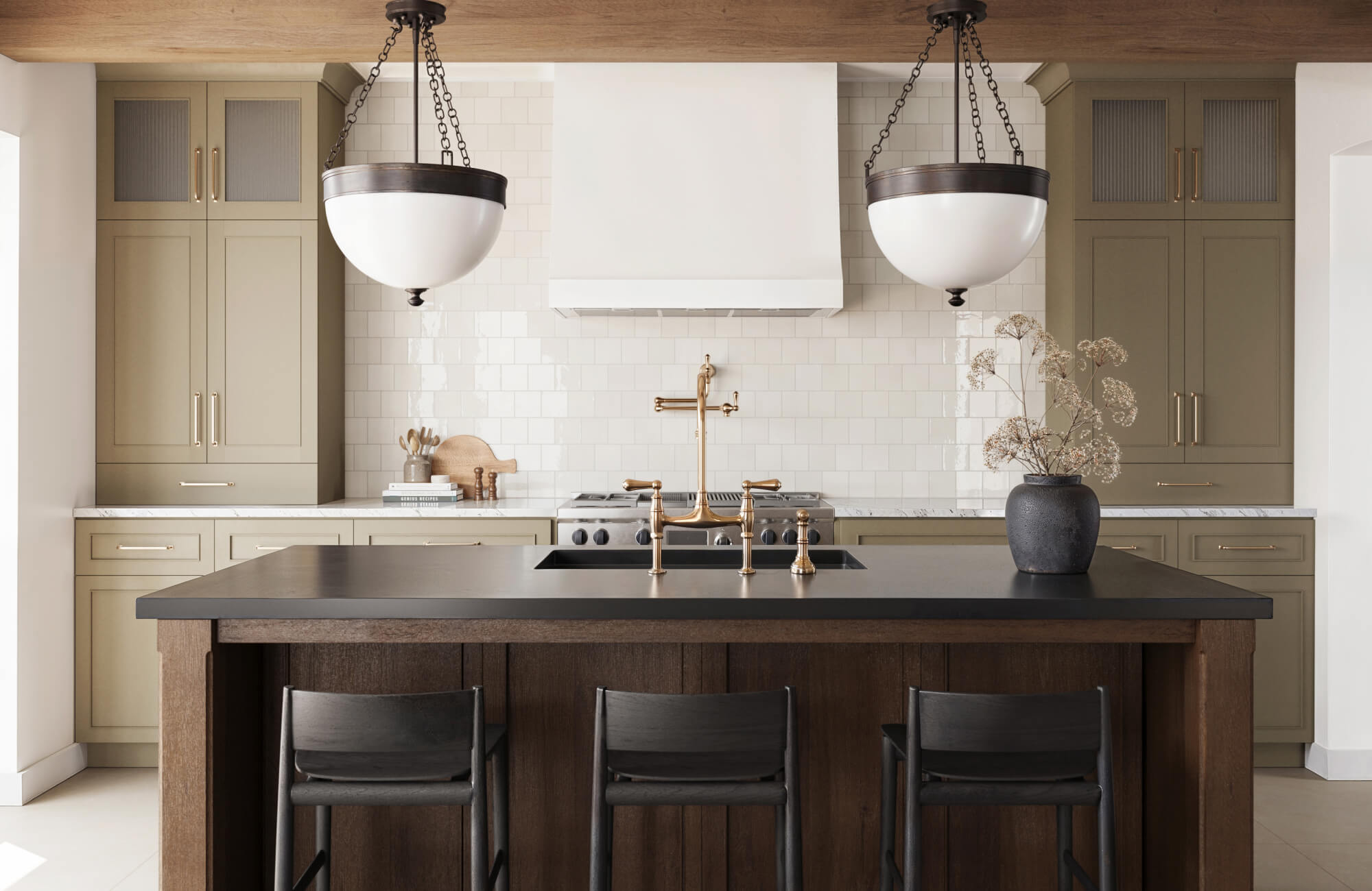 null Spacious kitchen featuring a dark wood island, brass fixtures, sage green cabinetry, and matching pendant lights suspended over a matte black countertop.