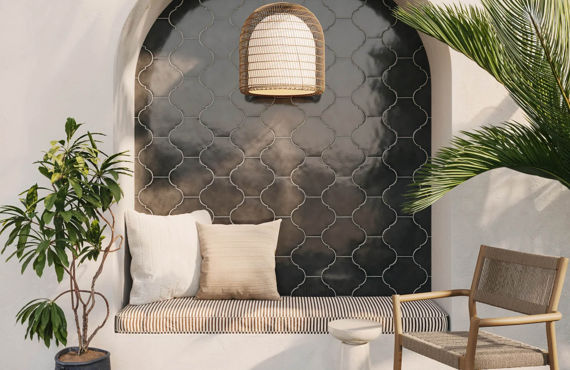 null A built-in bench framed by an arched niche combines layered neutral cushions, striped upholstery, and a dark patterned tile backdrop for striking visual contrast.
