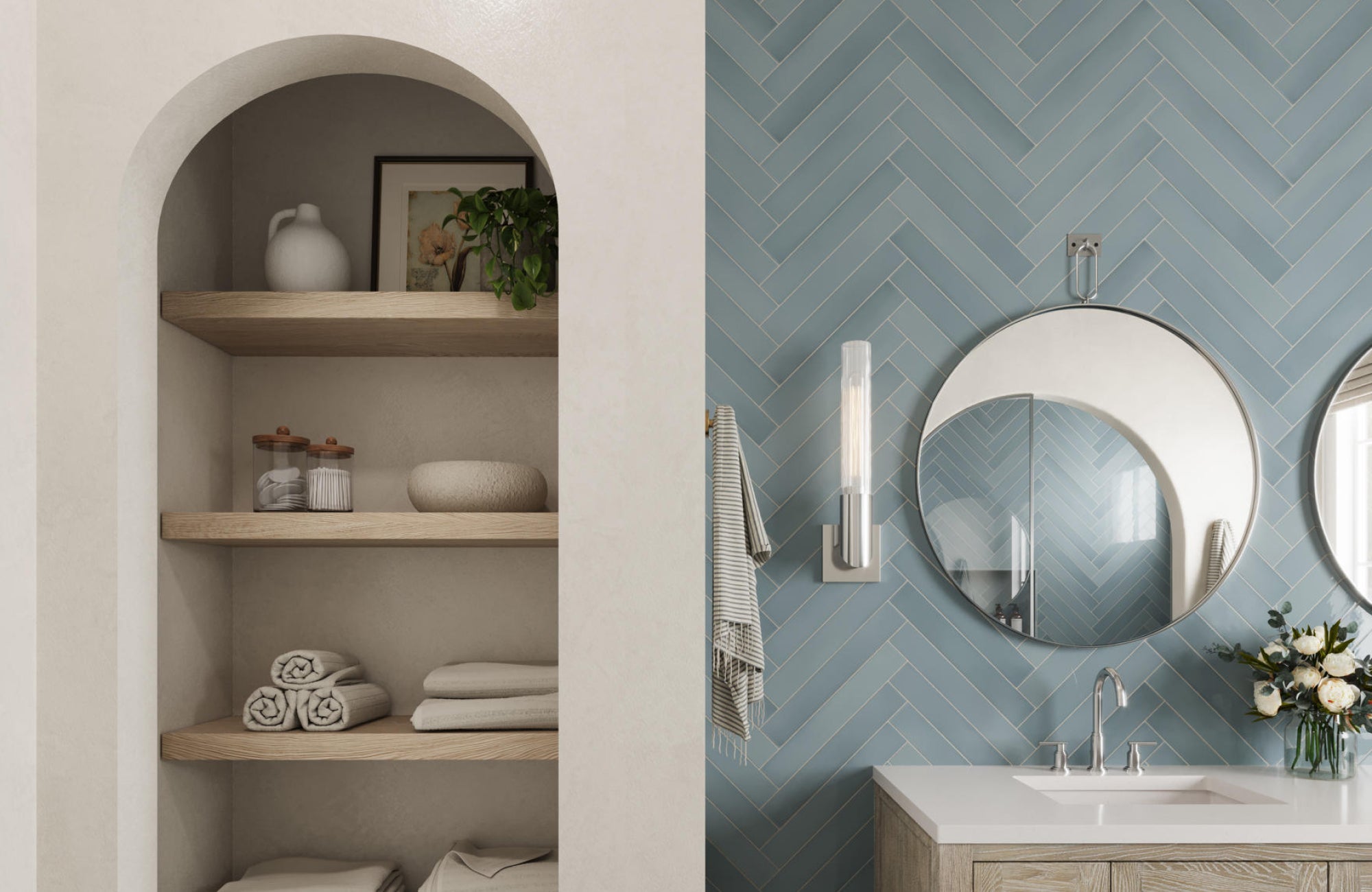 Bathroom with blue herringbone tiles and round mirrors reflecting light above a wood-toned vanity.