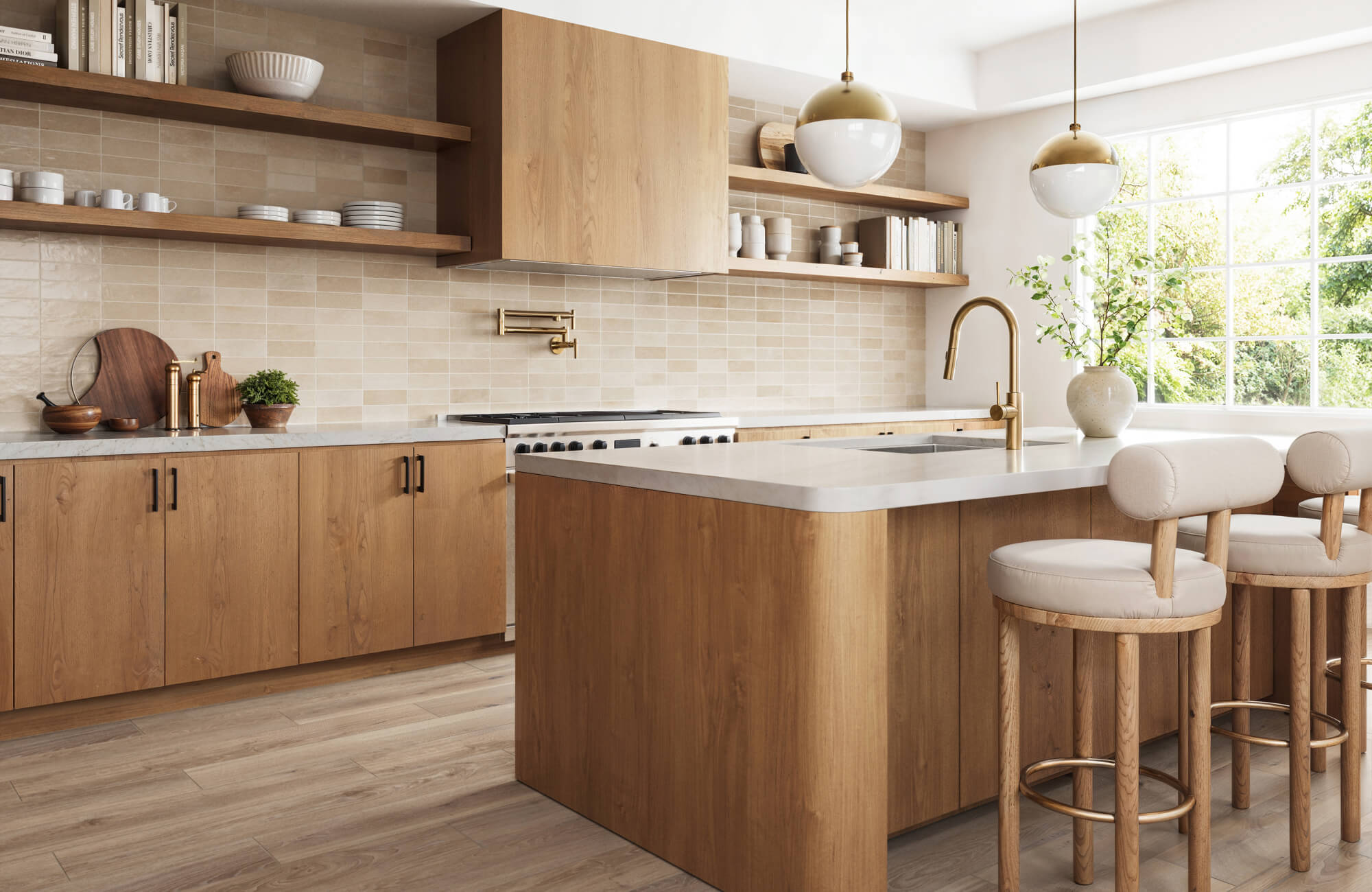 null Bright kitchen featuring wood cabinetry, a quartz countertop island, cream upholstered stools, brass pendant lights, and open shelves styled with ceramics and cookbooks.