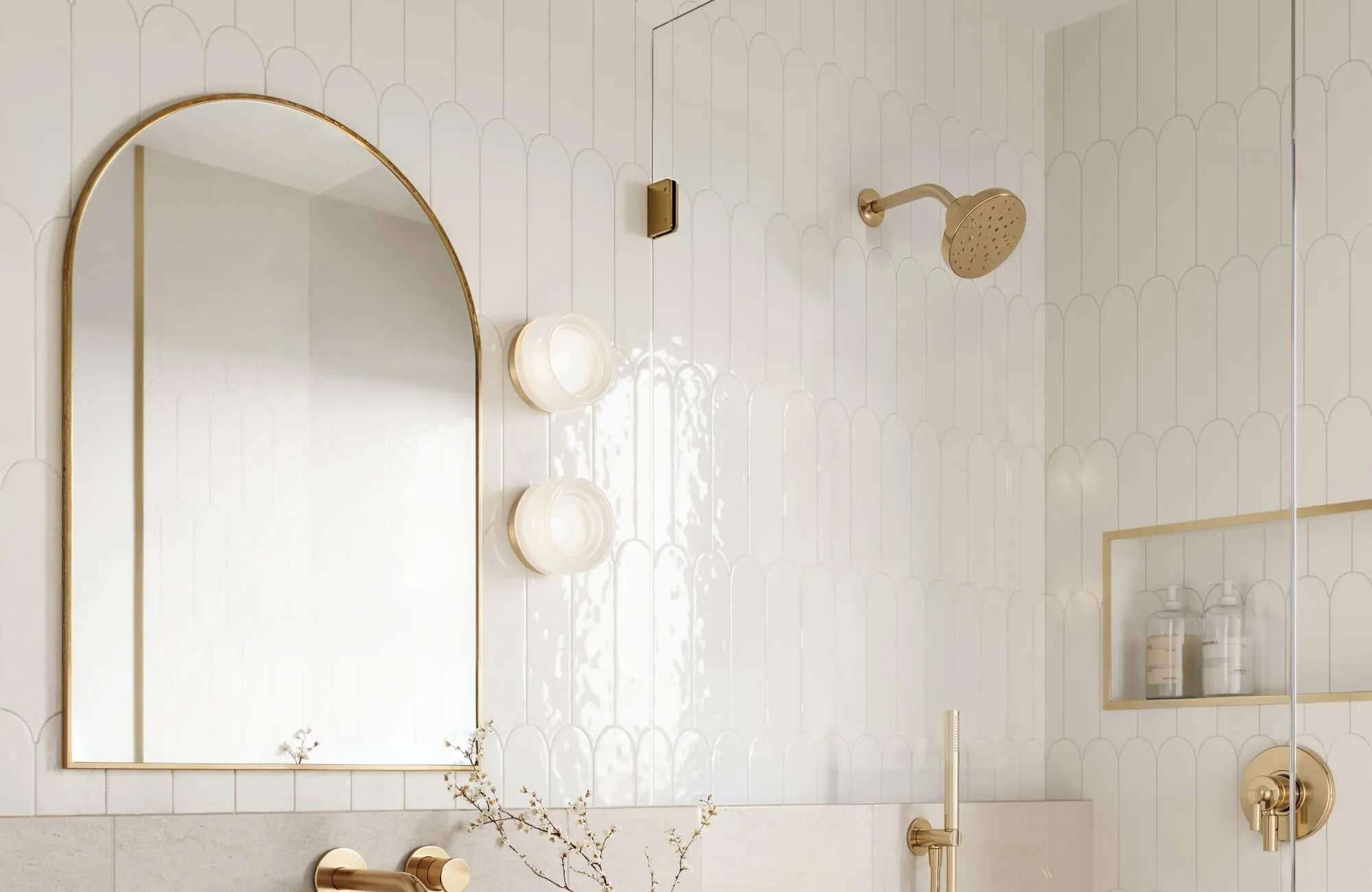Bathroom with white scallop ceramic wall tile, arched brass mirror, and brushed gold fixtures creating a refined spa-inspired look