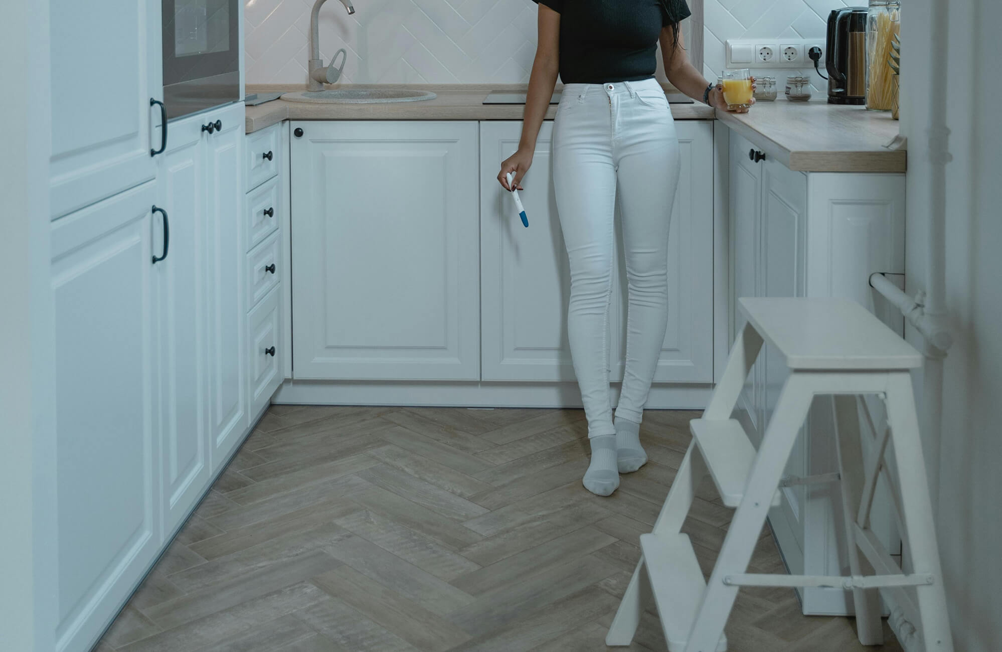 null Cozy kitchen with white cabinetry and countertops complemented by rustic wood-look herringbone floor tile for a warm, inviting feel.