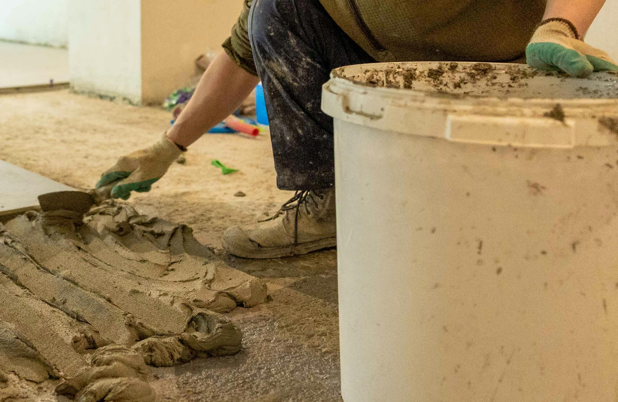 null Worker preparing mortar on the floor for installing herringbone floor tile, ensuring a durable and precise layout.