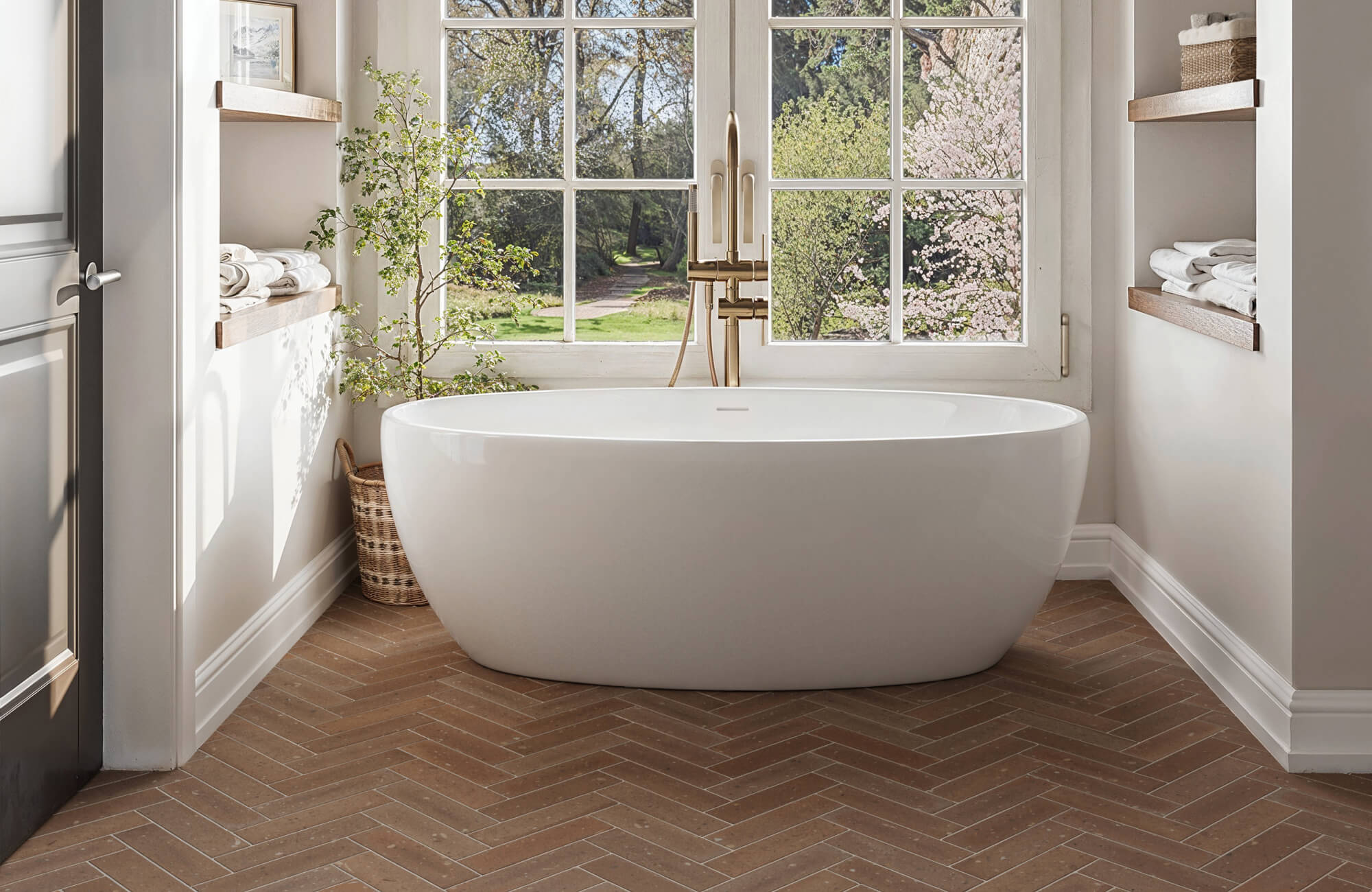 null Serene bathroom with a freestanding tub, large windows, and warm brown herringbone floor tile creating a cozy, spa-like ambiance.