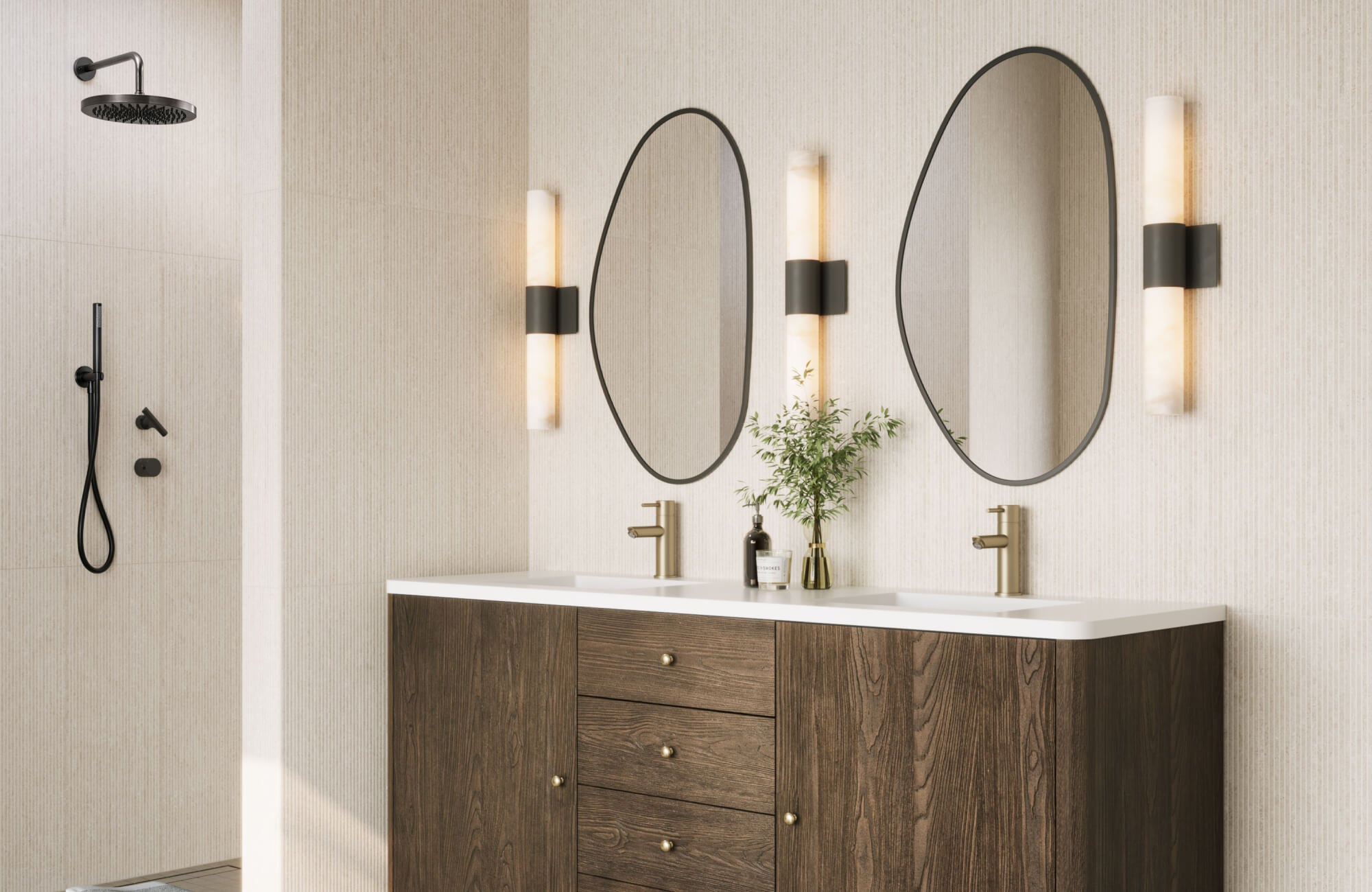 Modern dual vanity setup featuring asymmetric frameless mirrors, warm wall lighting, brushed brass fixtures, and a walk-in shower with matte black fittings.